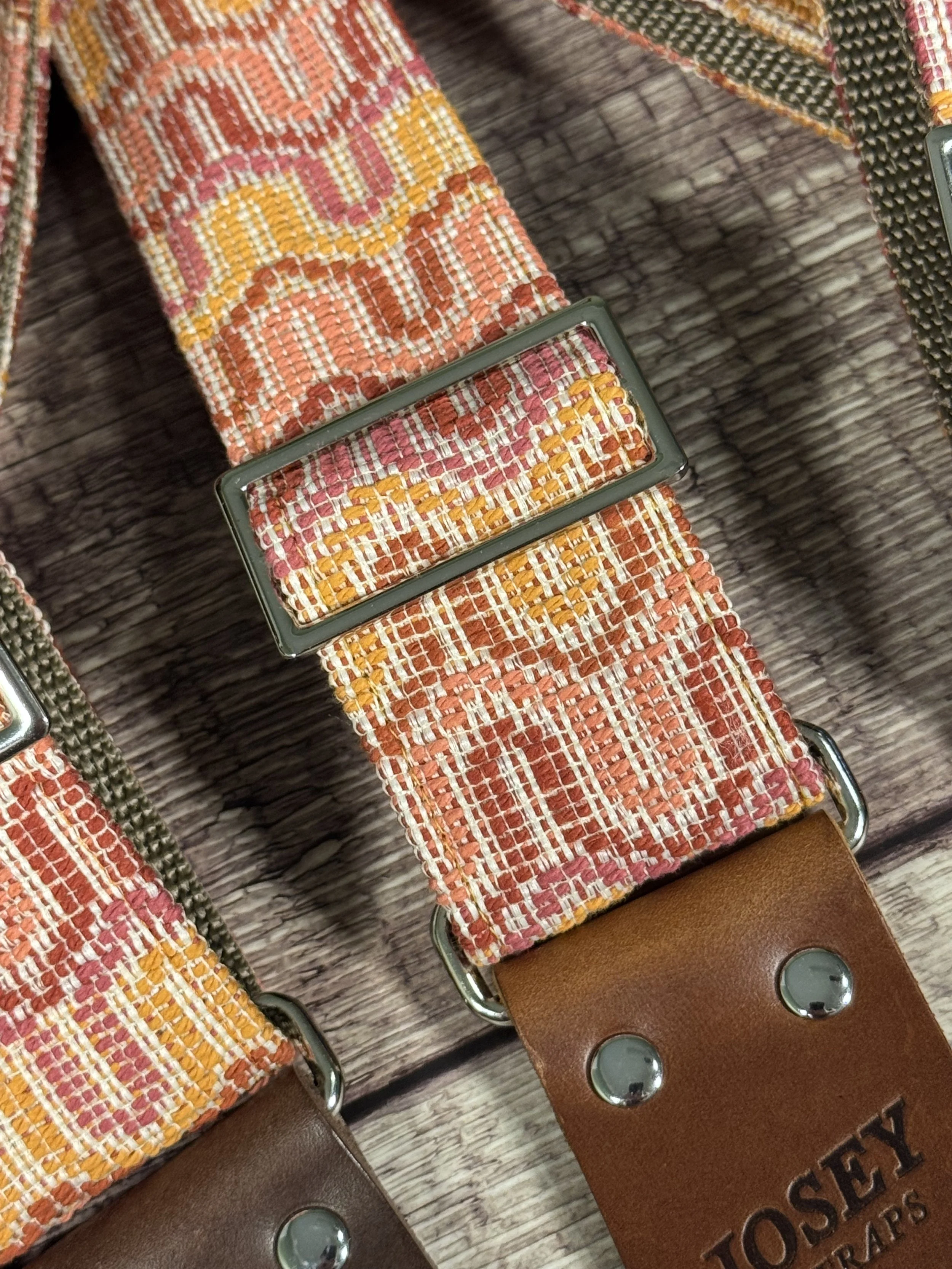 Vintage disco-inspired woven guitar straps in terracotta and gold tones by Josey Straps.  These straps are set on wood backdrop.