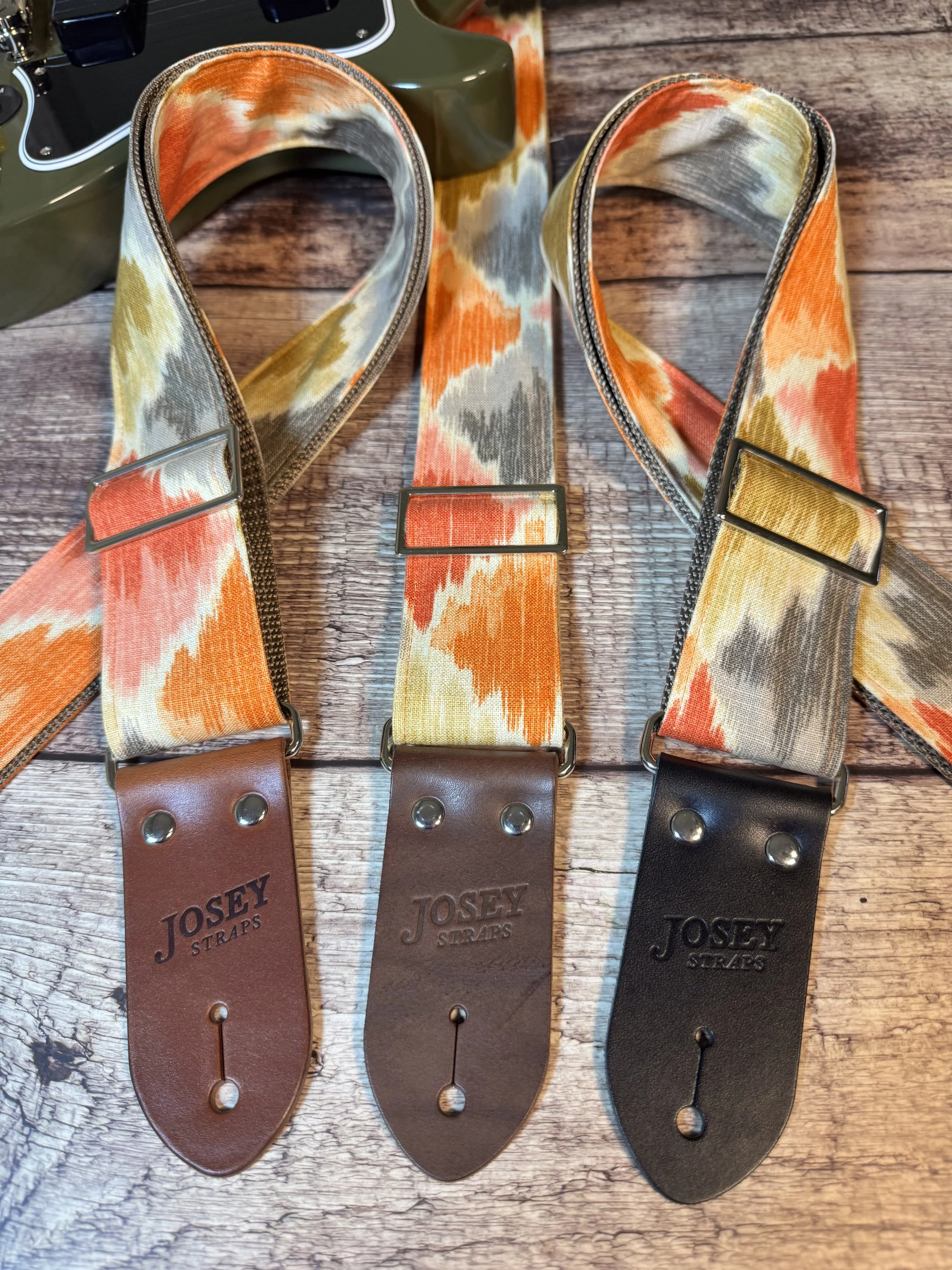 Southwestern themed guitar straps on wooden background.
