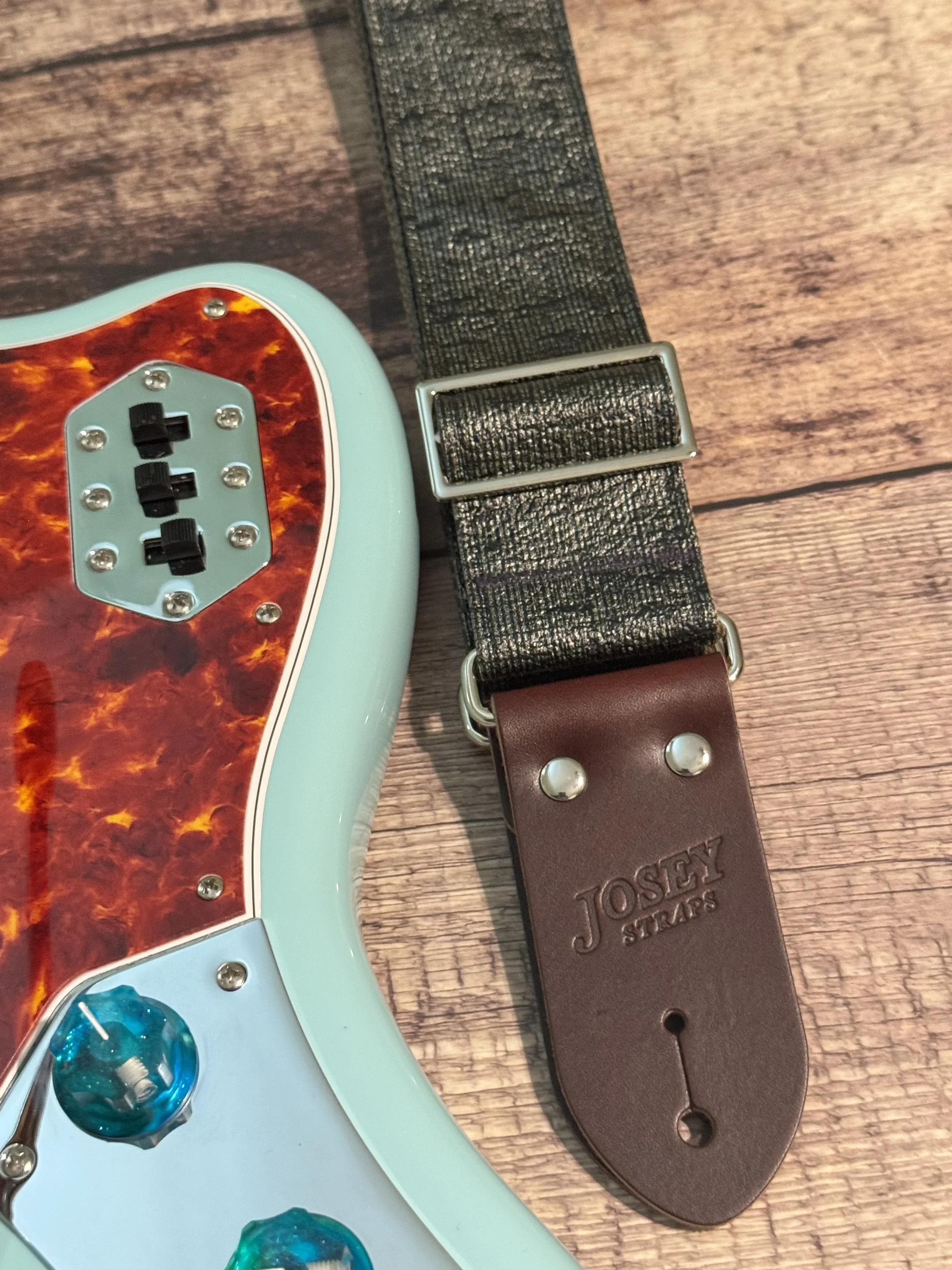 Pewter Slub guitar strap next to a blue guitar.