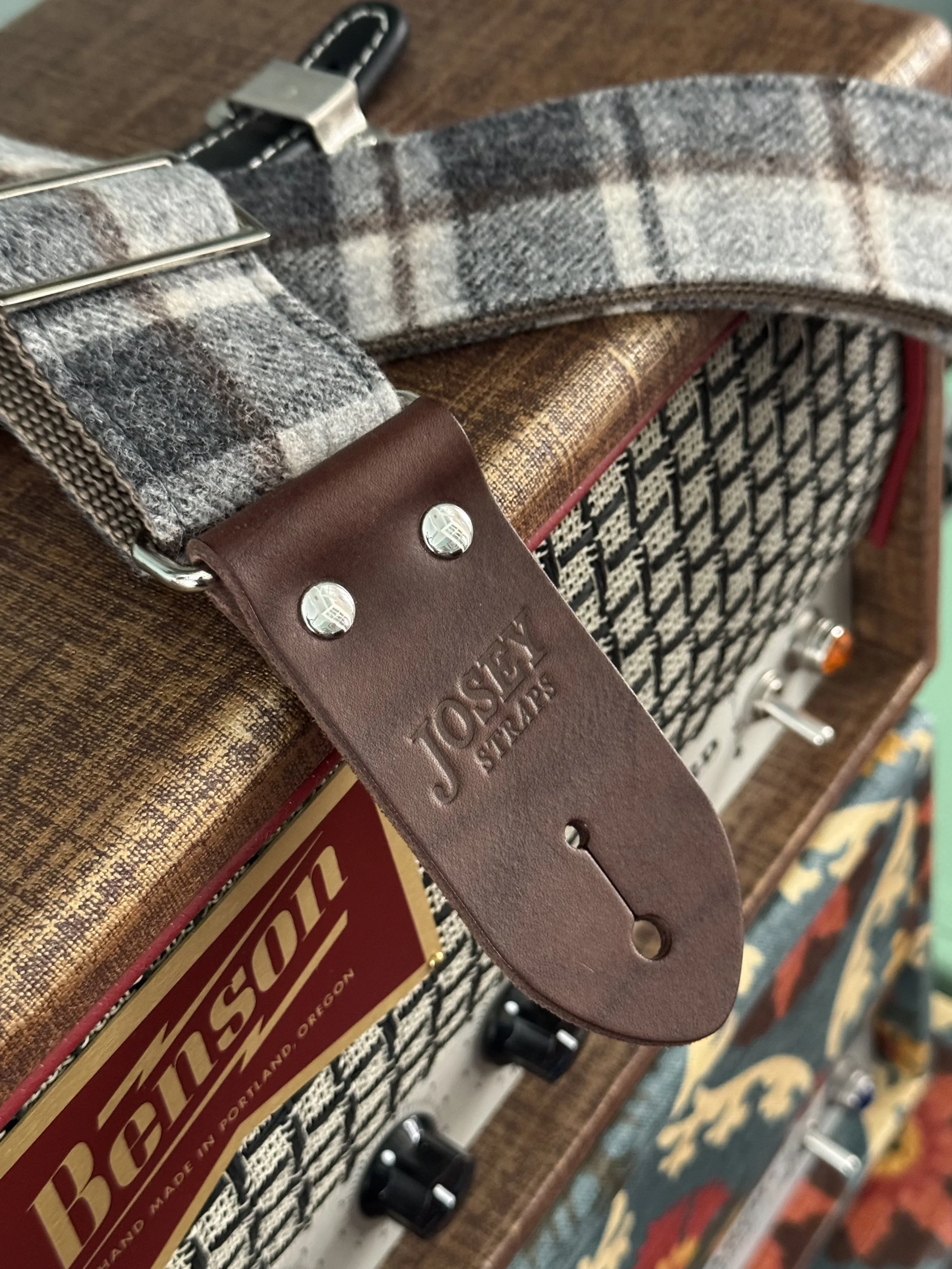 Vintage style grey plaid guitar straps on guitar amp.