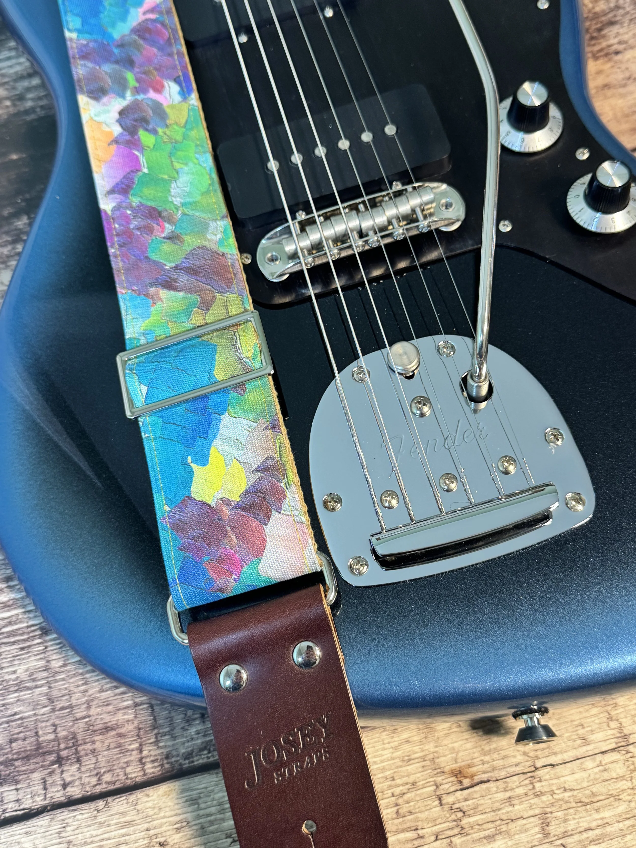 Impasto handmade guitar strap by Josey Straps featuring a vibrant abstract painterly pattern in blue, green, purple, and yellow with premium leather ends.