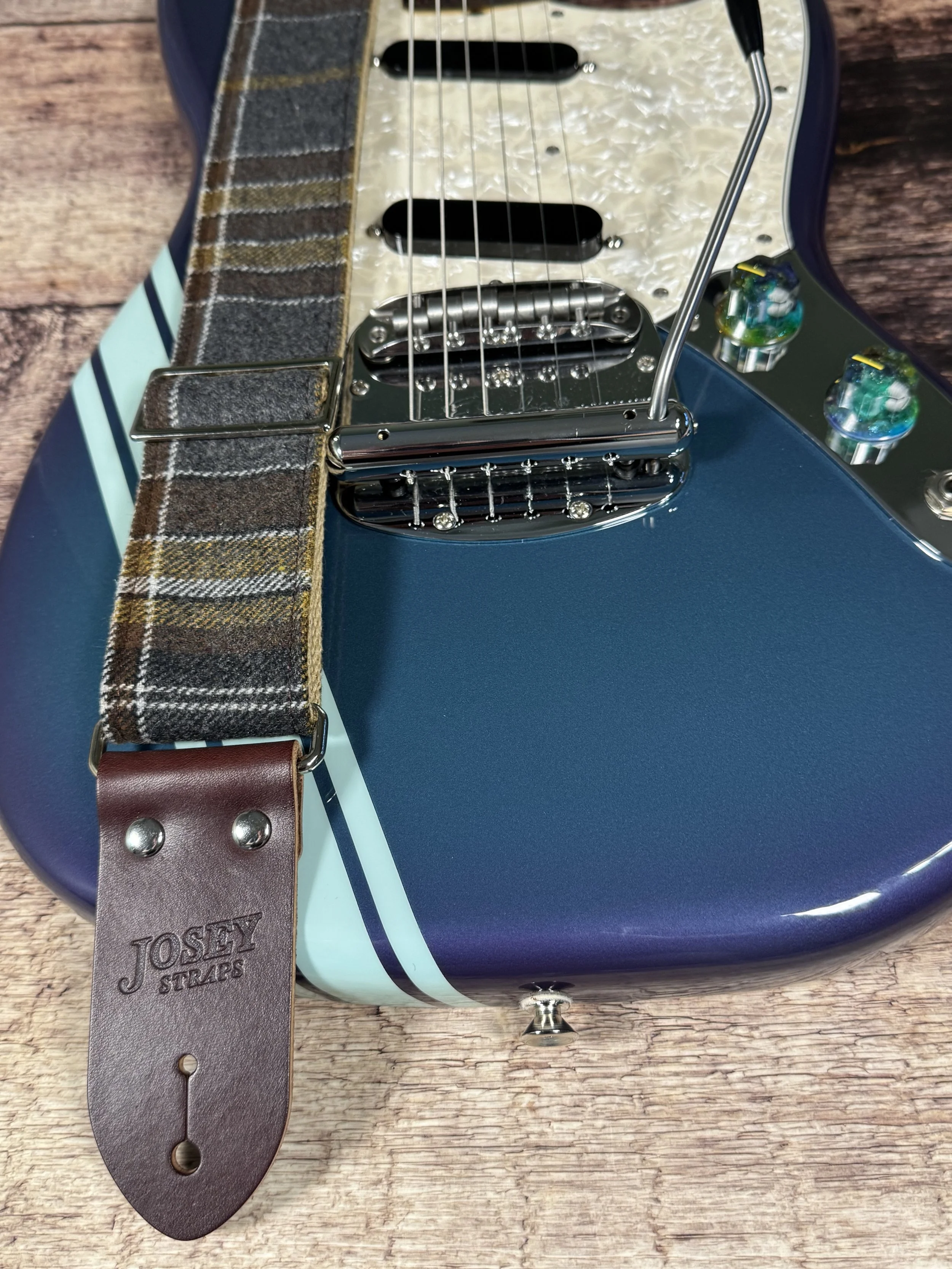 Ashes plaid guitar strap with leather ends by Josey Straps displayed on wood background