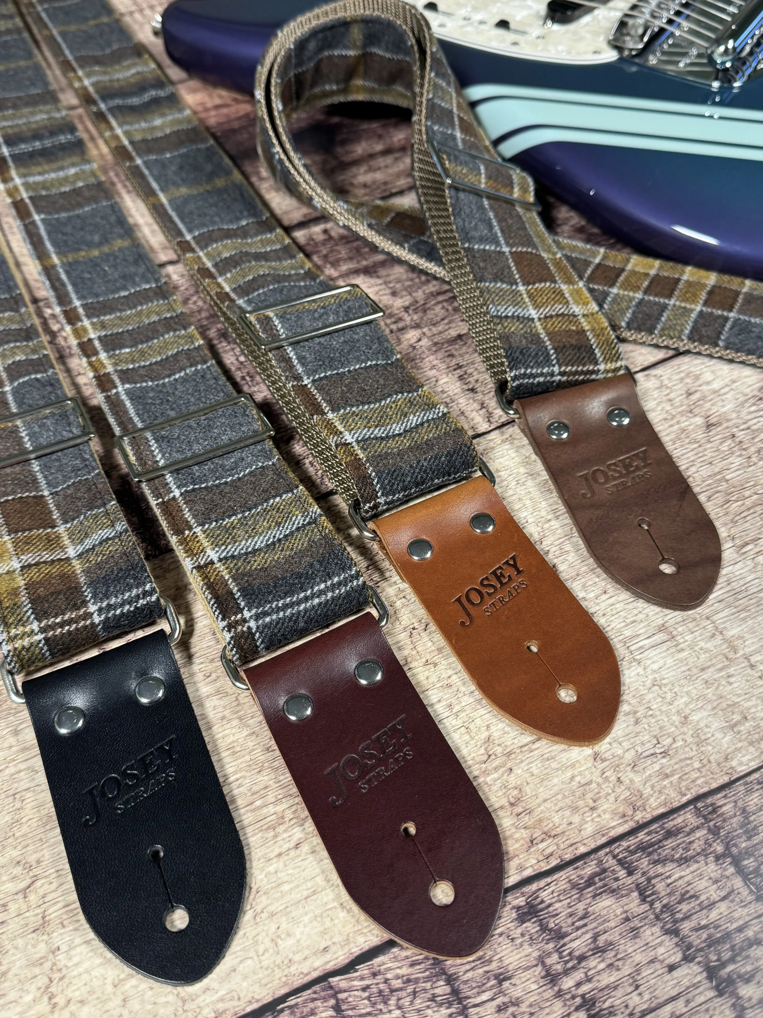 Ashes plaid guitar strap with leather ends by Josey Straps displayed on wood background