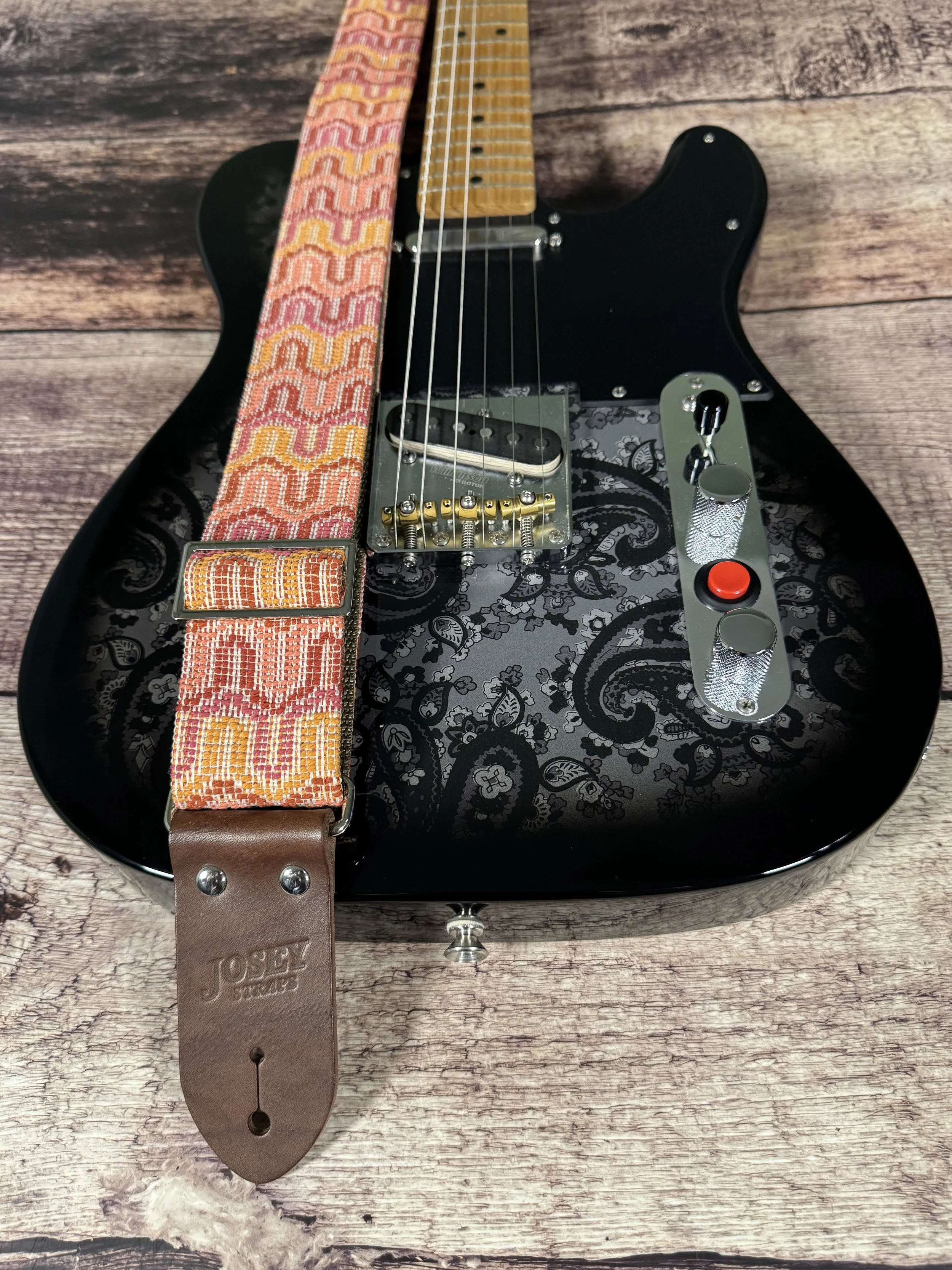 Vintage disco-inspired woven guitar strap in terracotta and gold tones by Josey Straps.  These strap is set on a black electric guitar.