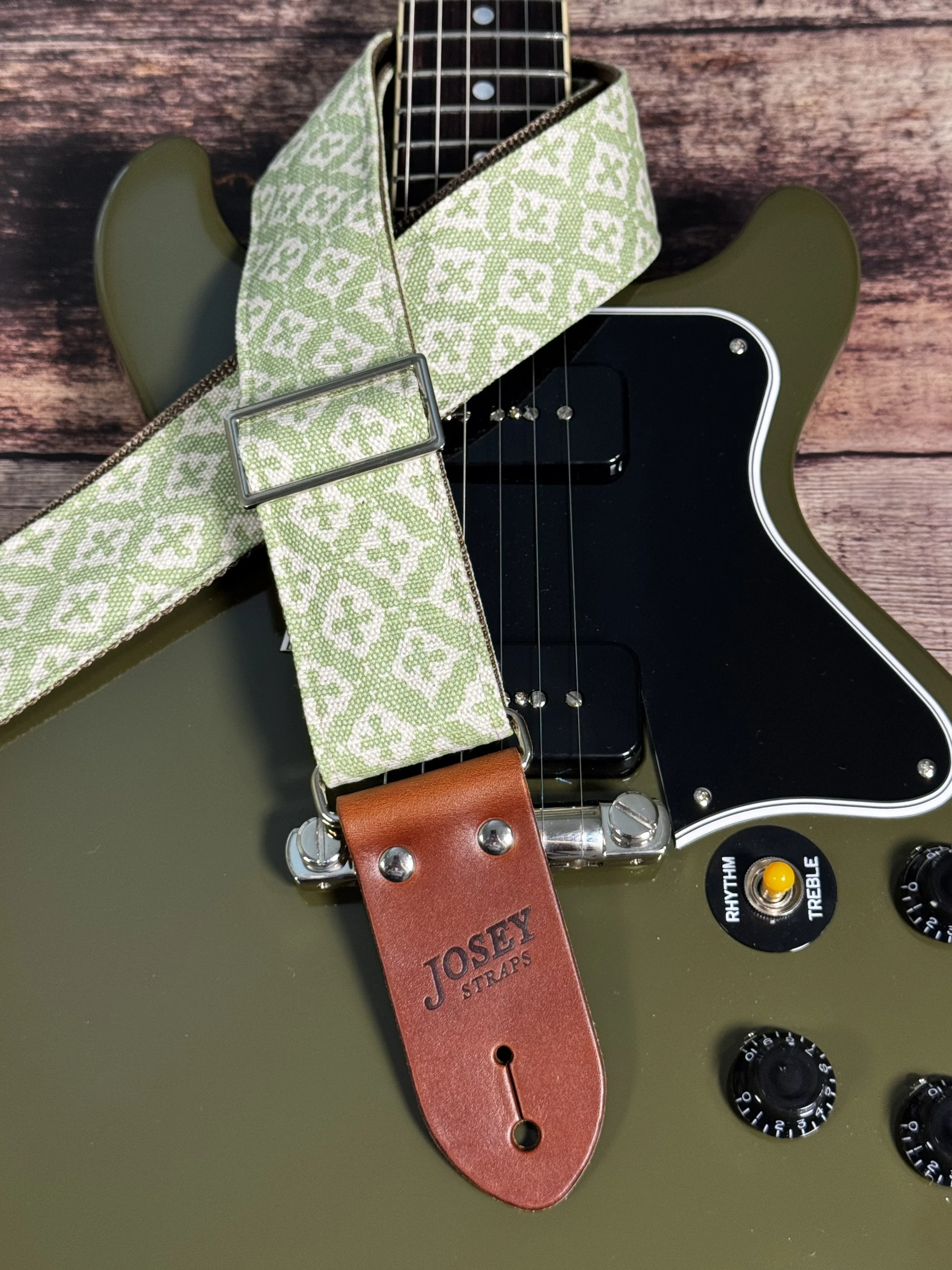 The Green House handmade guitar strap by Josey Straps featuring a sage green and cream geometric pattern with premium leather ends.