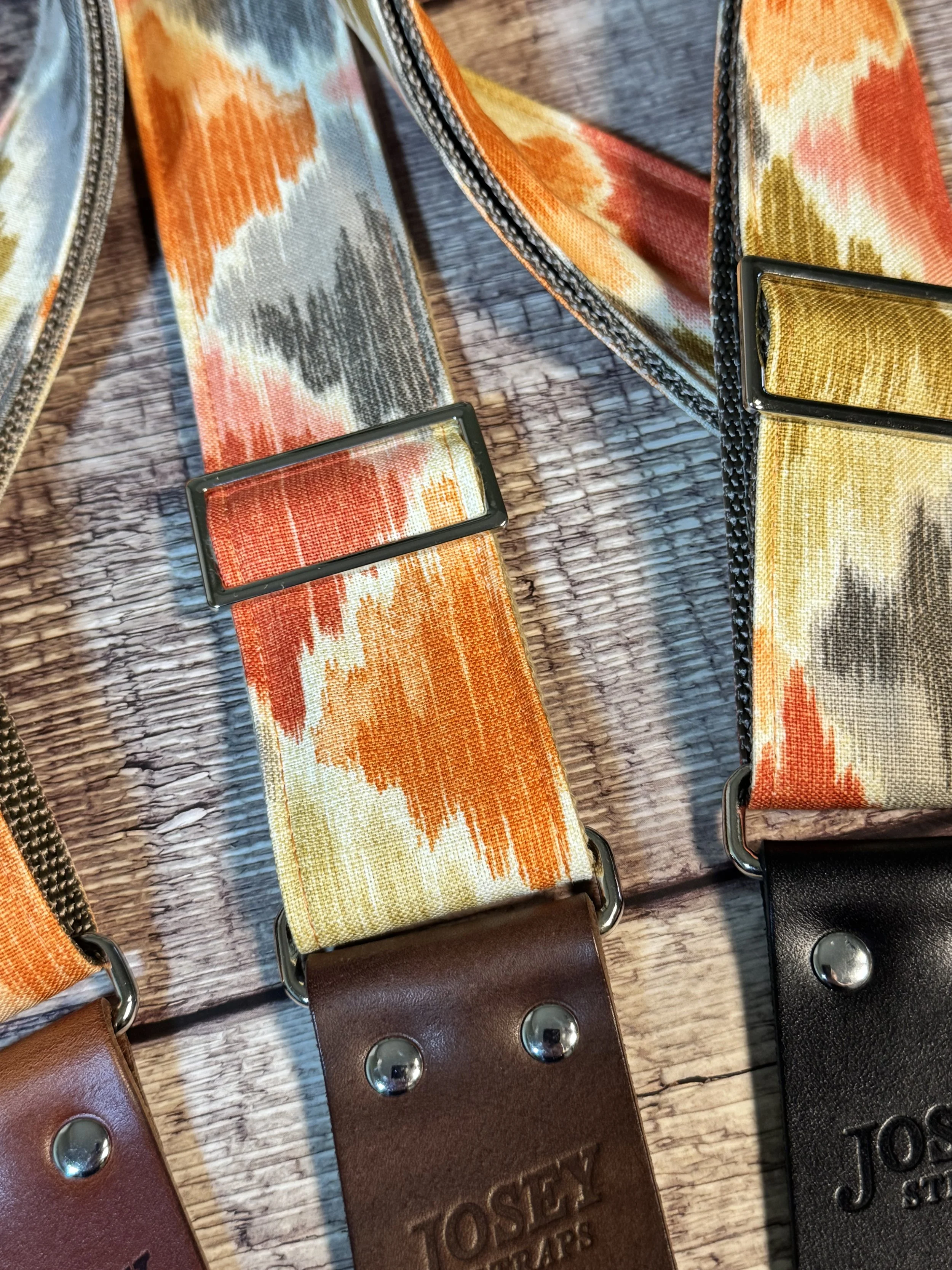 Southwestern themed guitar straps on wooden background.