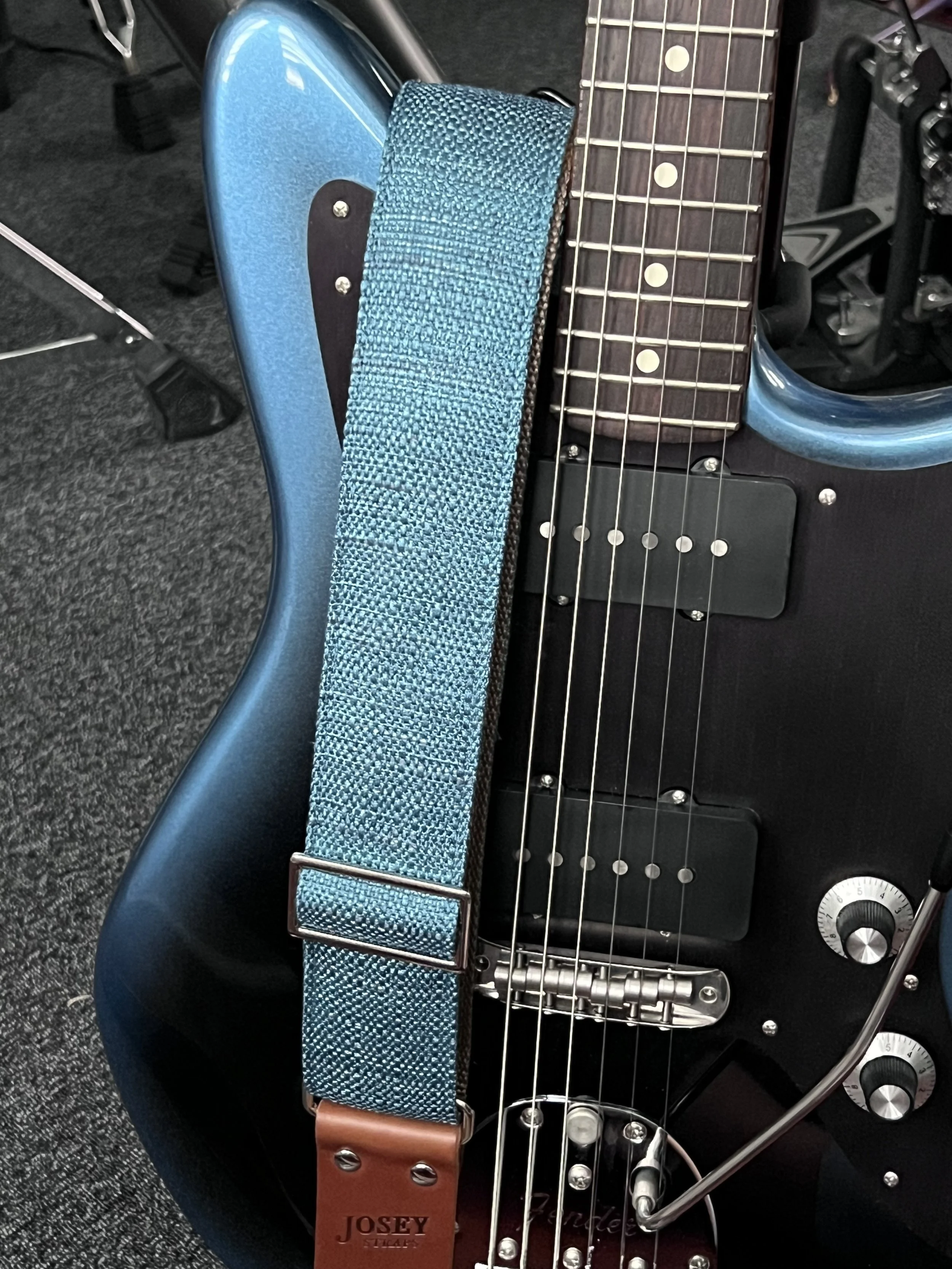 Peacock Blue woven guitar strap with blue-green texture and leather ends by Josey Straps on a blue and black guitar.