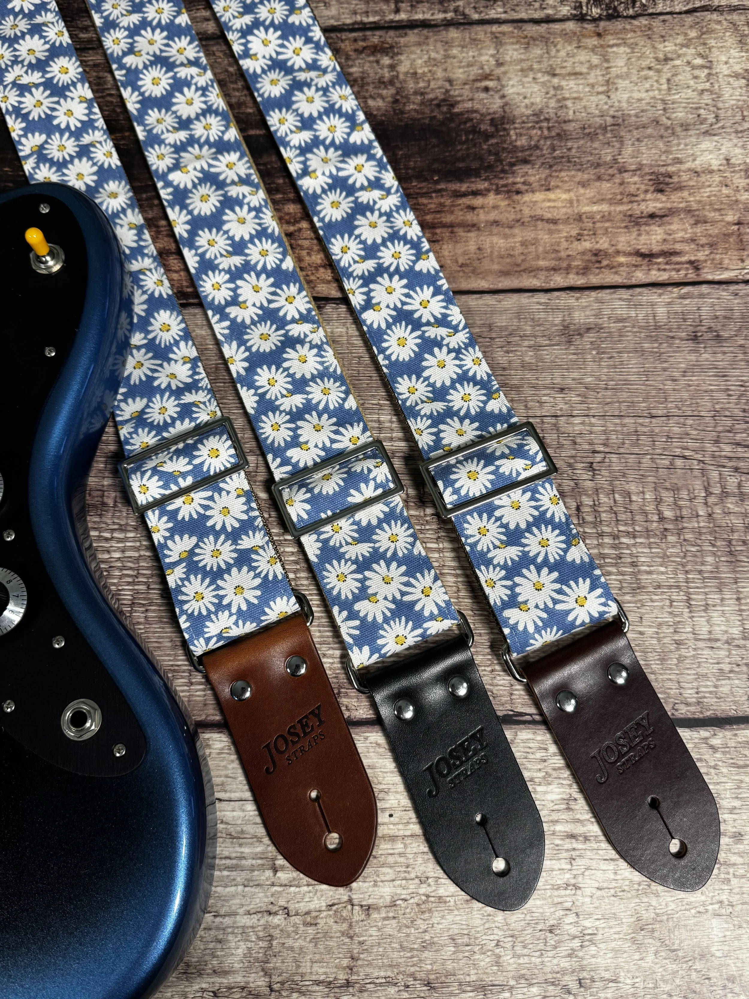 Daisy handmade floral guitar strap by Josey Straps featuring white daisies with yellow centers on a denim-blue background and premium leather ends.