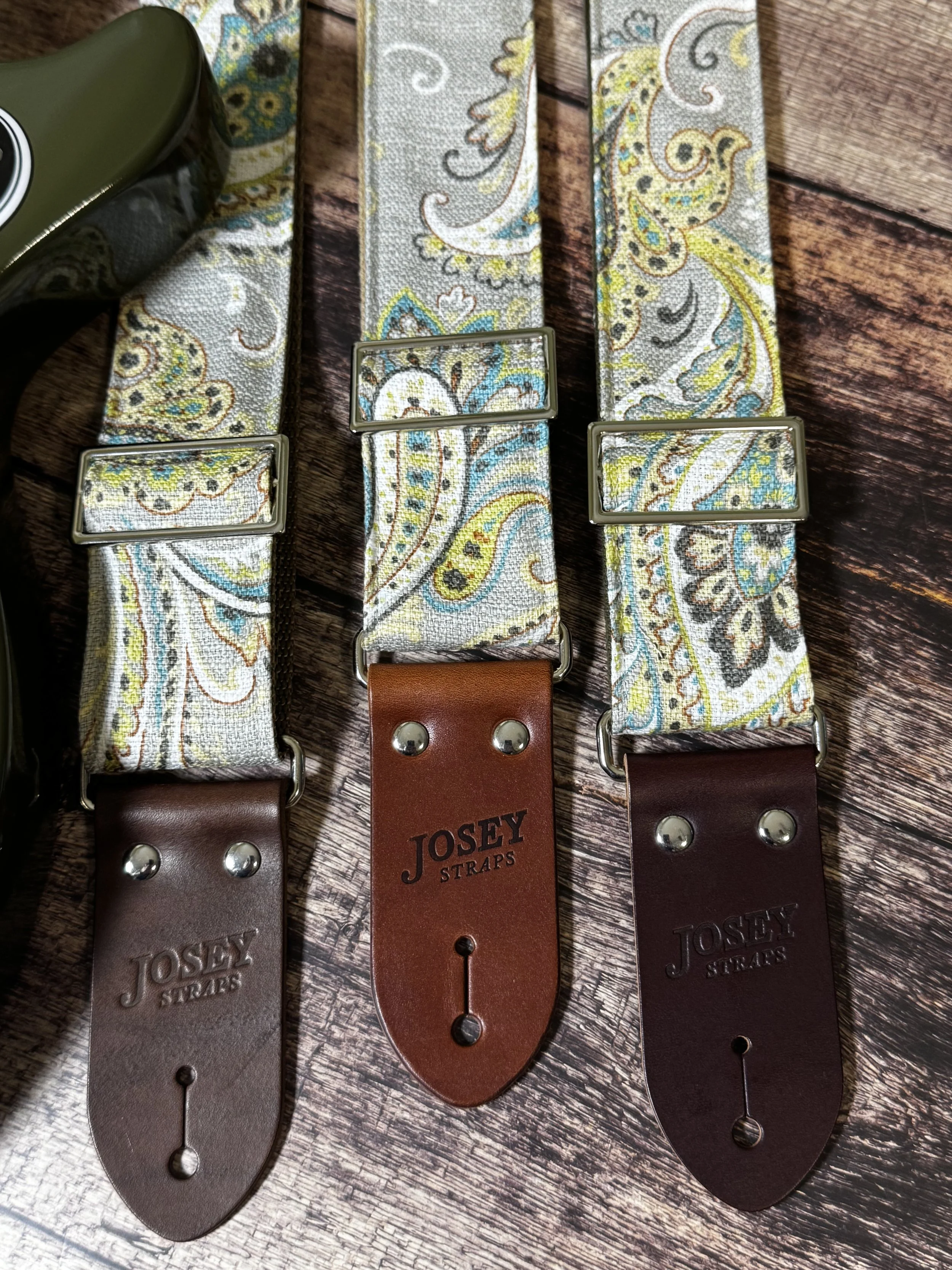 Graisley handmade paisley guitar strap featuring a gray, cream, blue, and mustard vintage-inspired pattern with premium leather ends.