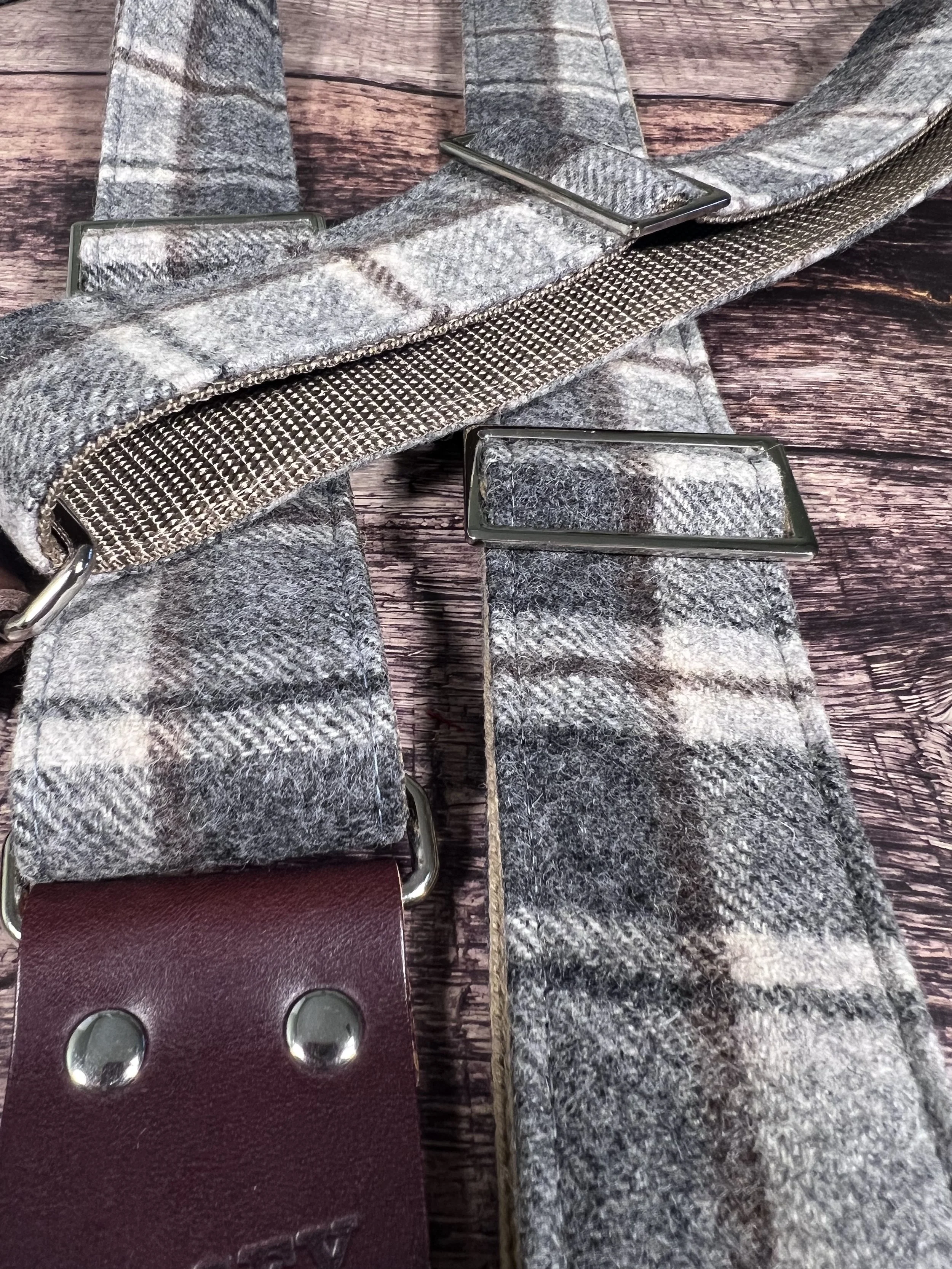 Vintage style grey plaid guitar straps on wooden floor.