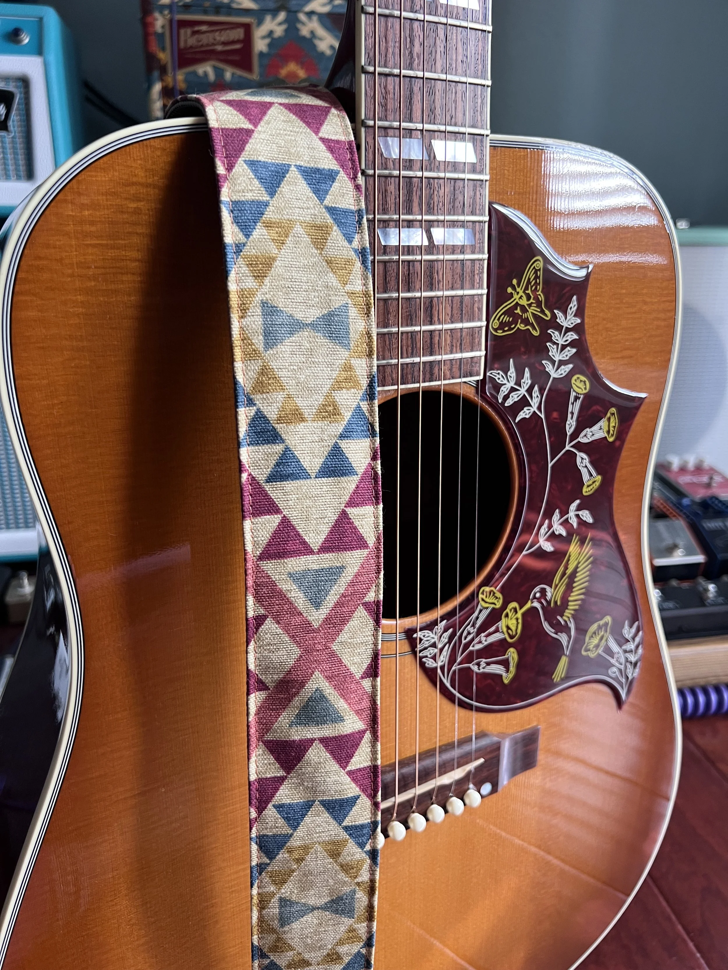 southwest style design guitar strap hanging over acoustic guitar with hummingbird pick guard