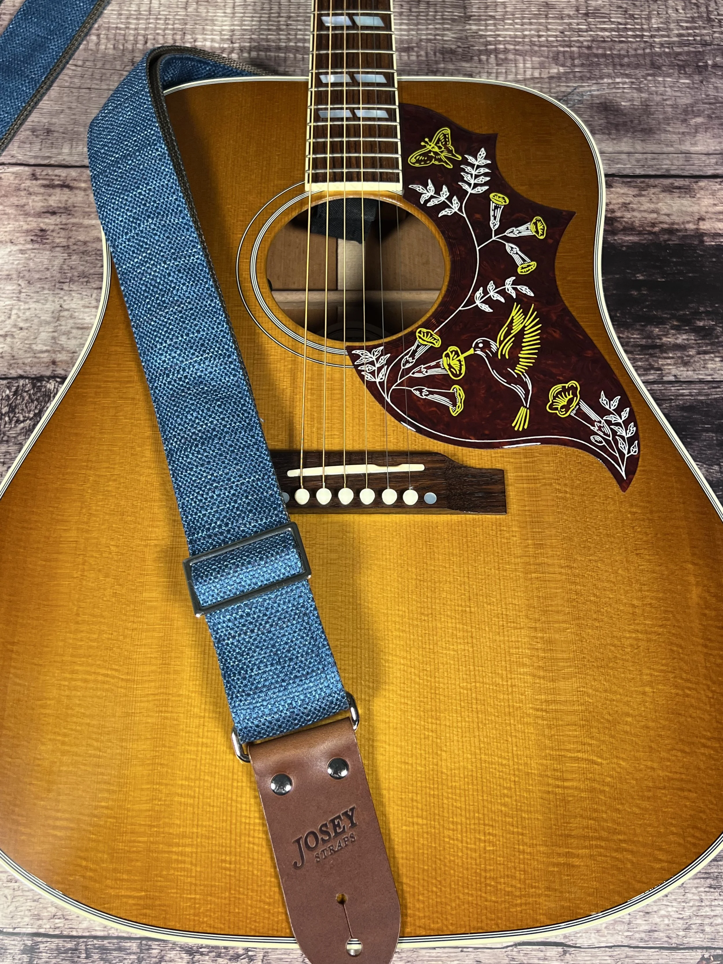 Peacock Blue woven guitar strap with blue-green texture and leather ends by Josey Straps on an acoustic guitar.