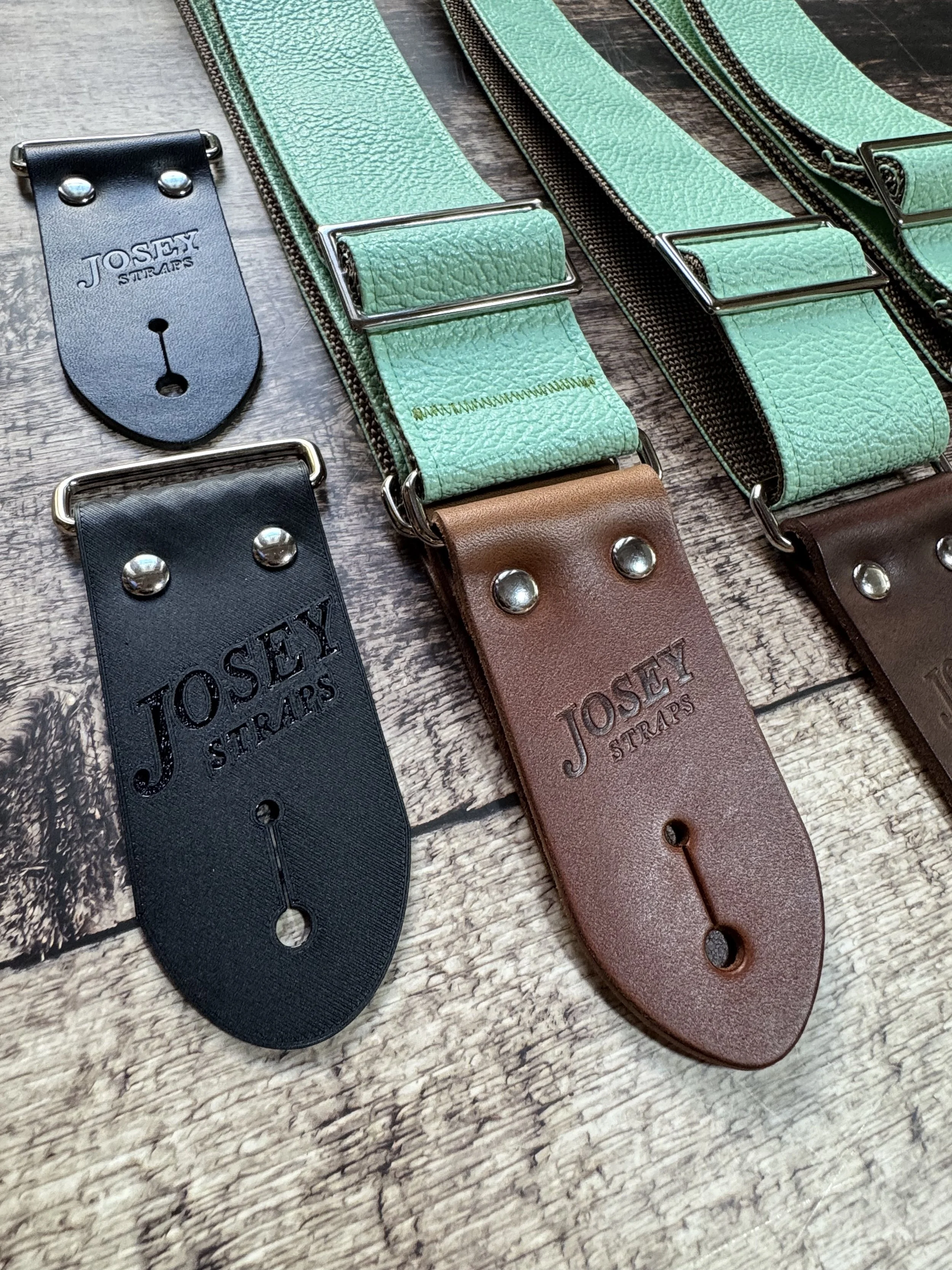 Seafoam green guitar straps on wooden floor.