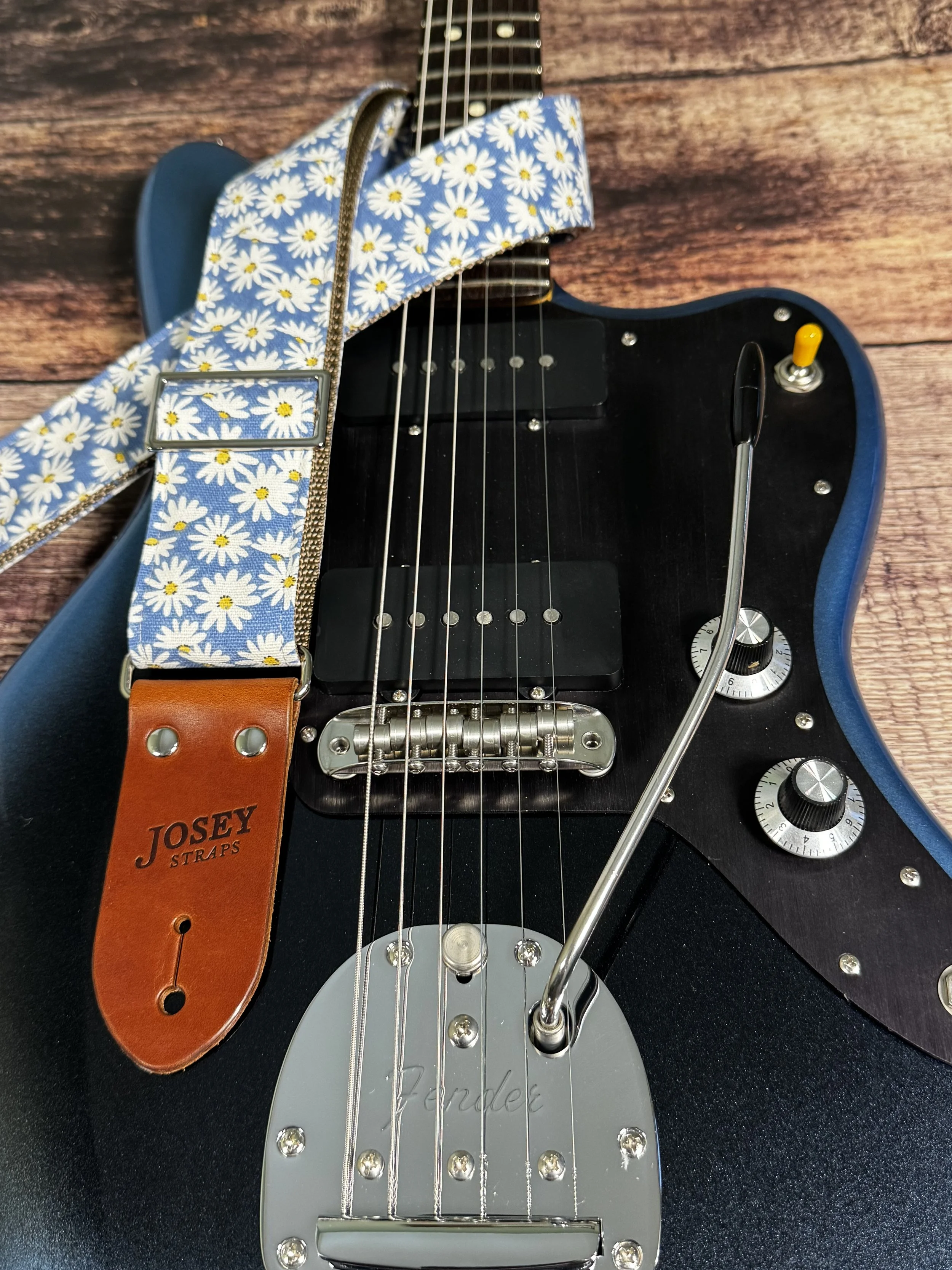 Daisy handmade floral guitar strap by Josey Straps featuring white daisies with yellow centers on a denim-blue background and premium leather ends.