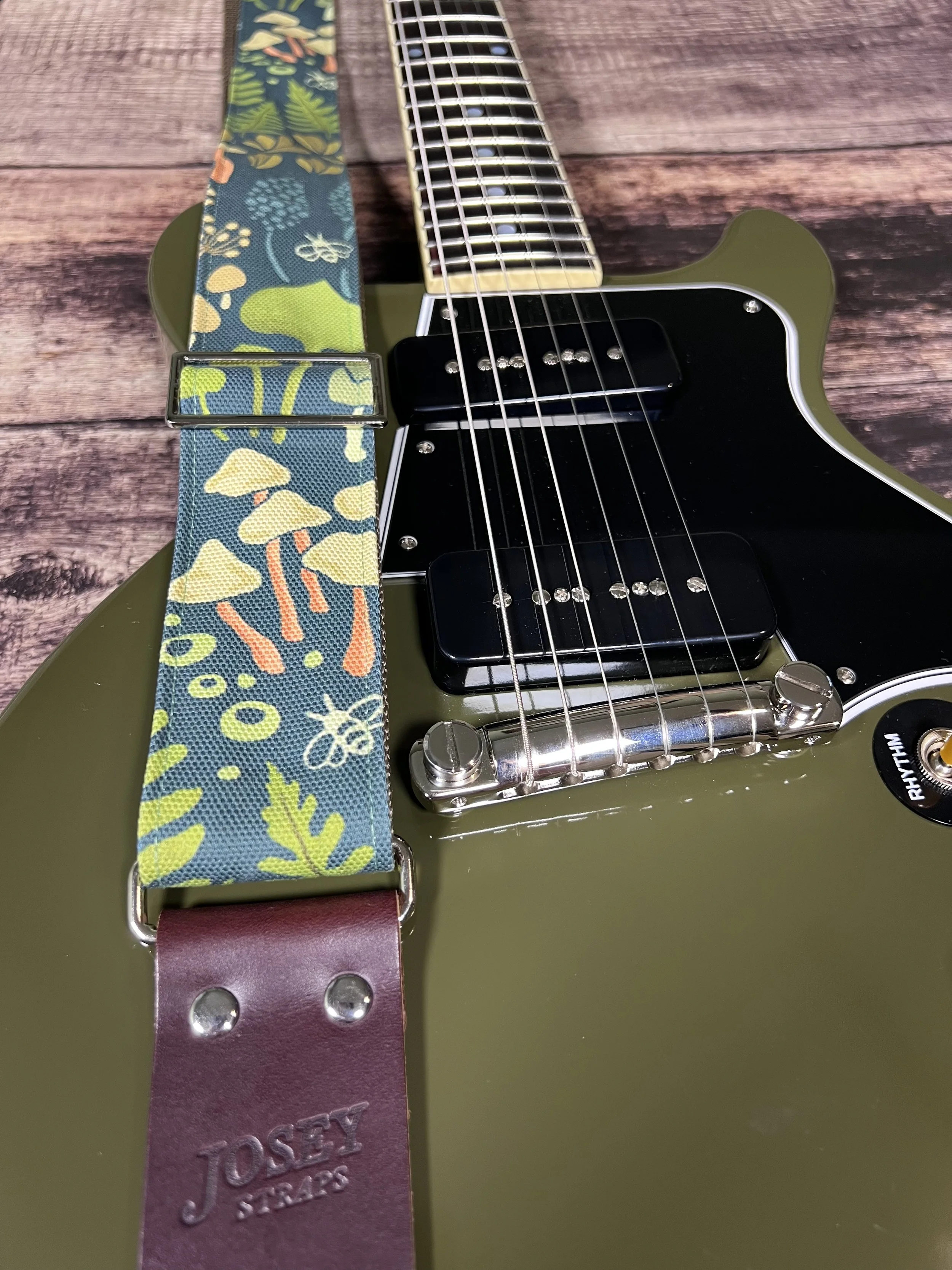 Dark botanical guitar straps on olive green guitar.