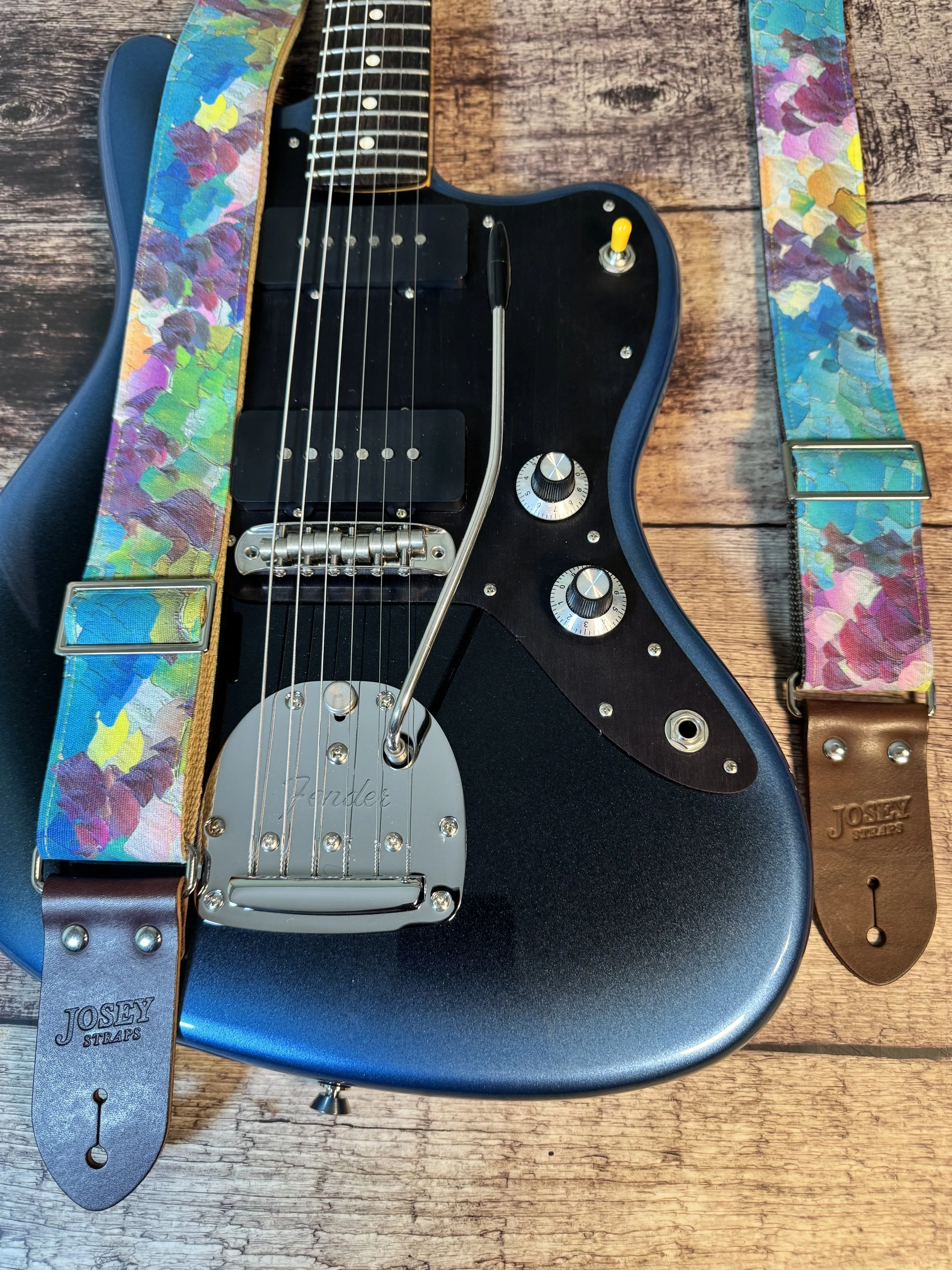 Impasto handmade guitar strap by Josey Straps featuring a vibrant abstract painterly pattern in blue, green, purple, and yellow with premium leather ends.