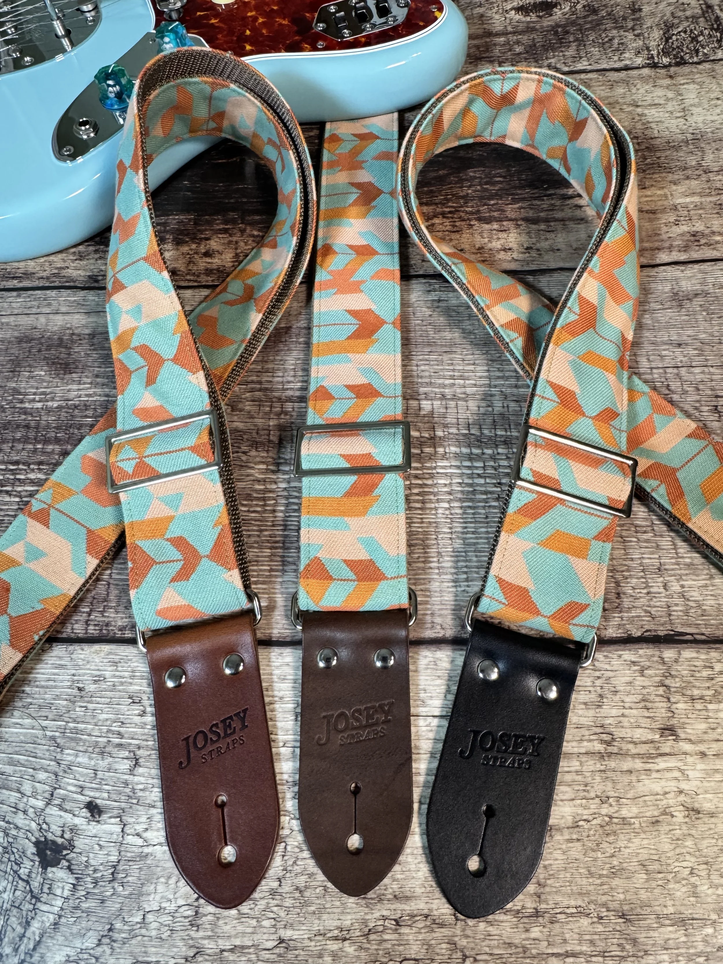Mesa Verde handmade guitar strap by Josey Straps featuring a geometric Southwestern-inspired pattern in turquoise, terracotta, orange, and cream with premium leather ends.
