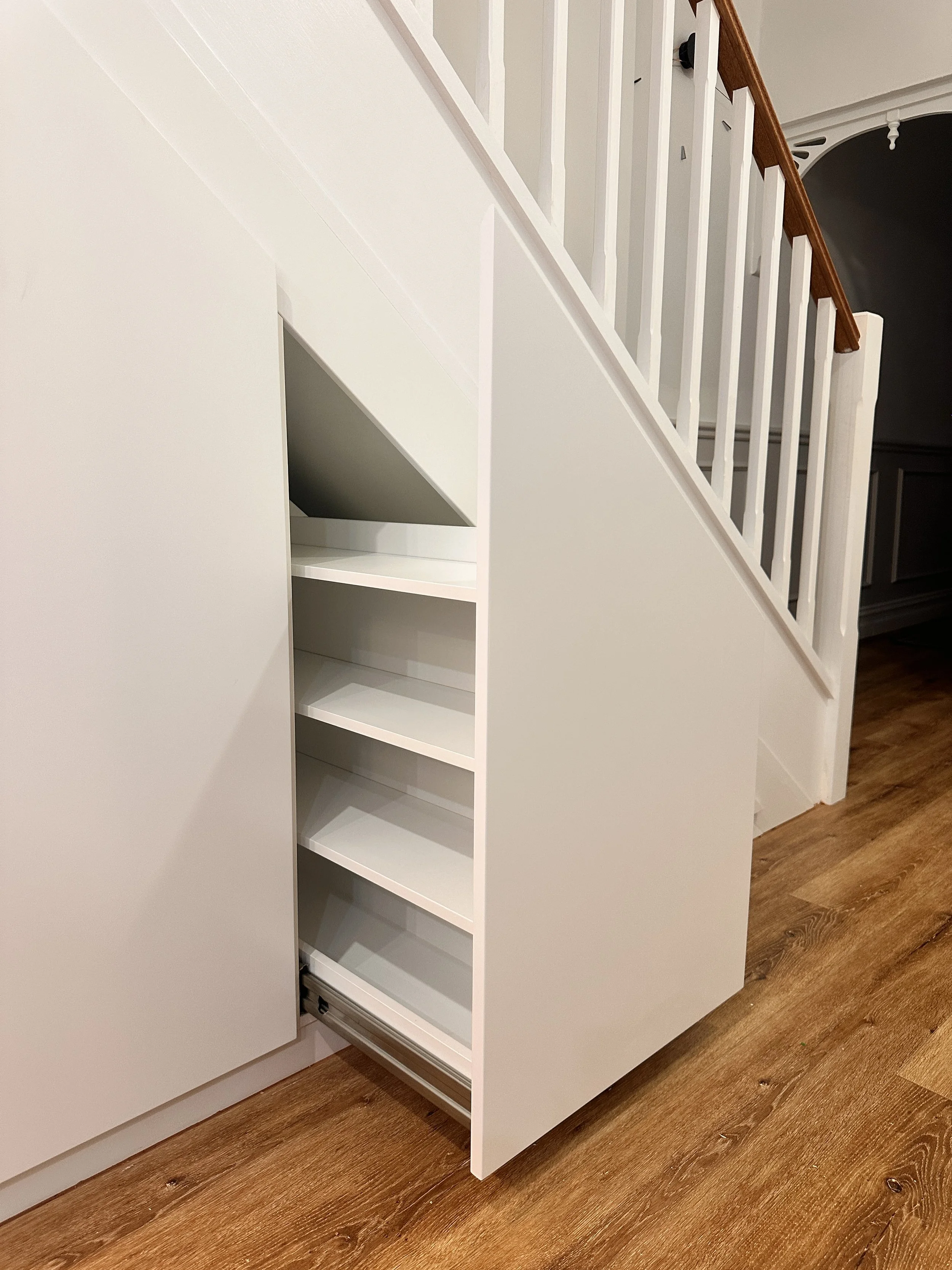Custom staircase storage cabinetry with drawers and hidden shelving