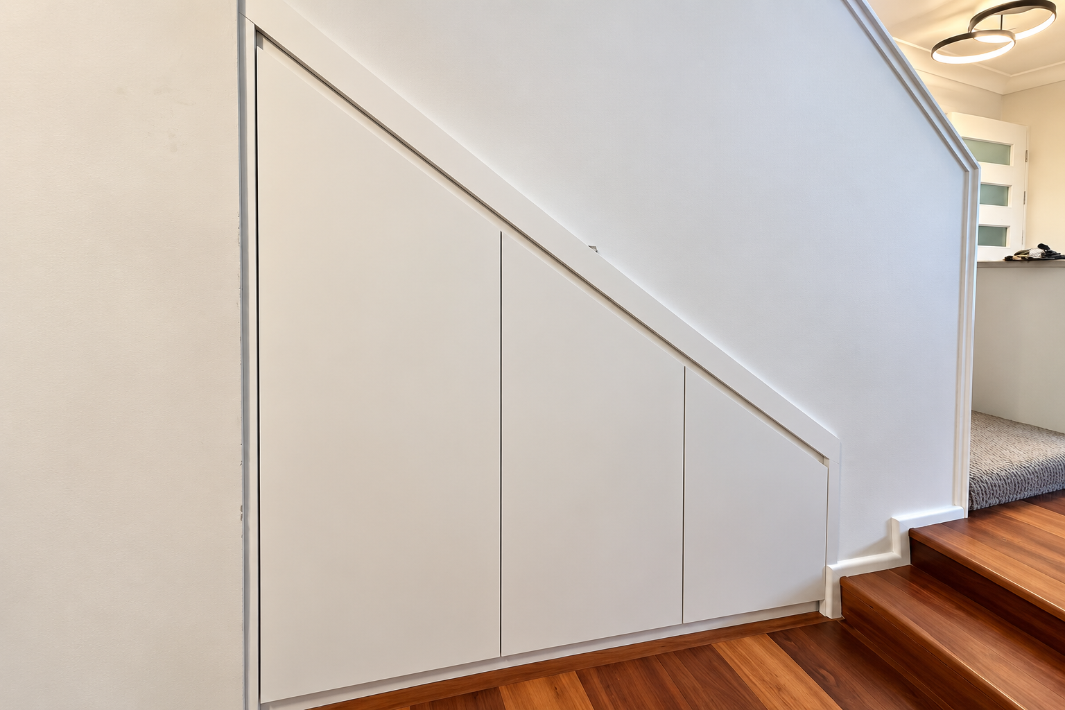 Custom under-stairs cabinetry in Neutral Bay with seamless white polyurethane fronts