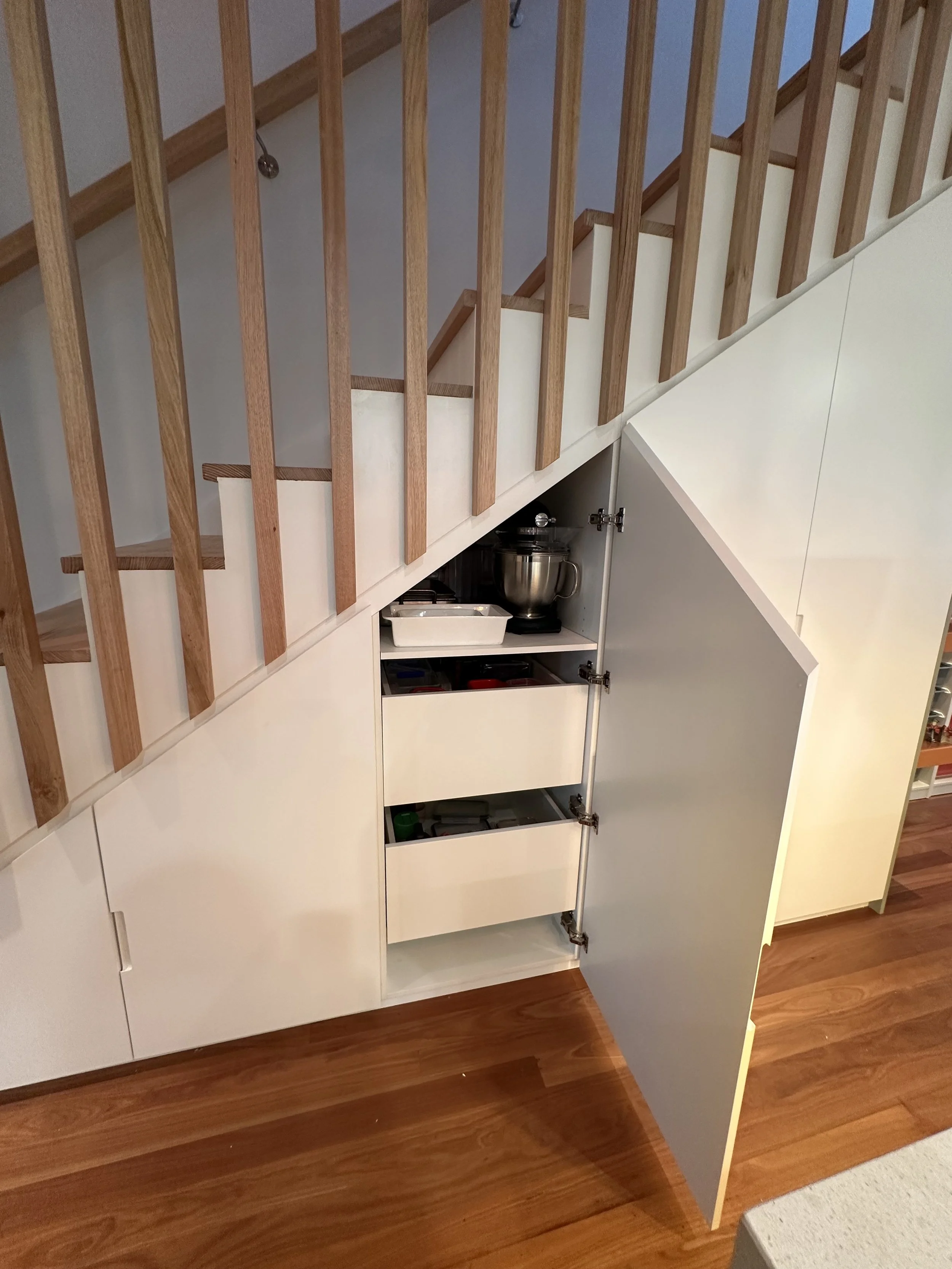 Custom under stairs cabinetry with pull-out drawers and adjustable shelving