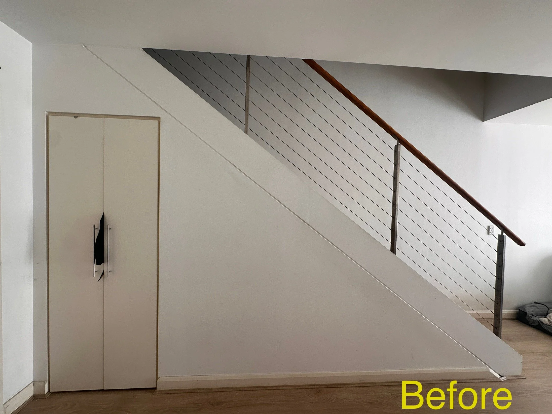 Under stairs space with plain white wall and no cabinetry installed