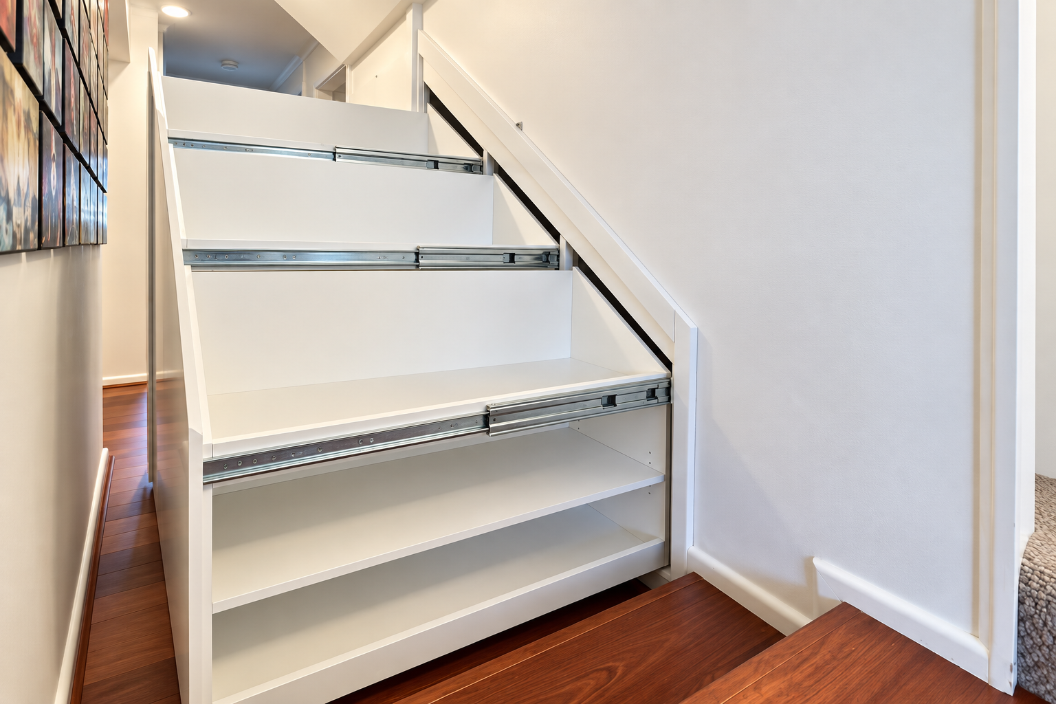 Three custom under-stairs pull-out storage units open in Neutral Bay