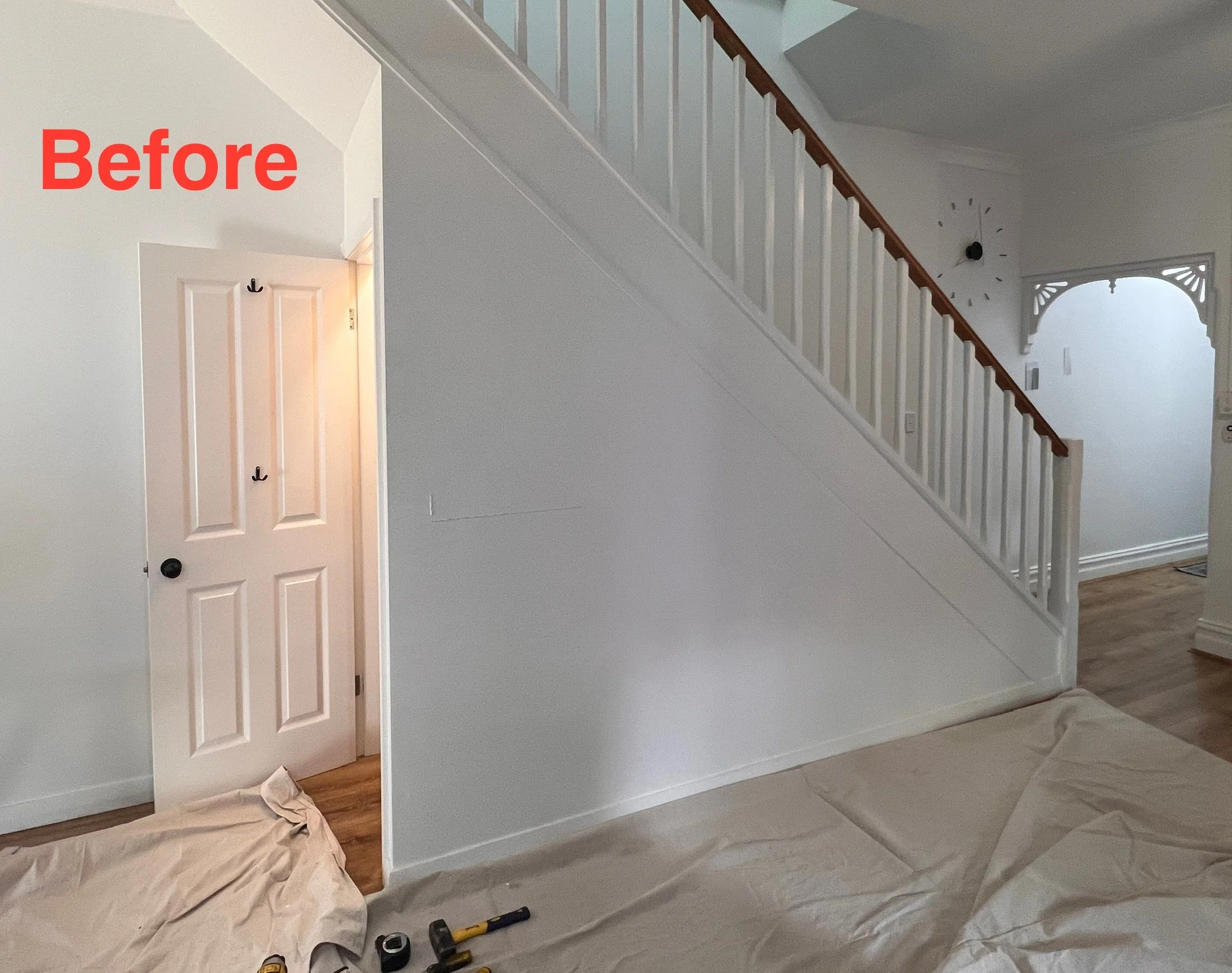 Before staircase with railing and unused wall space underneath