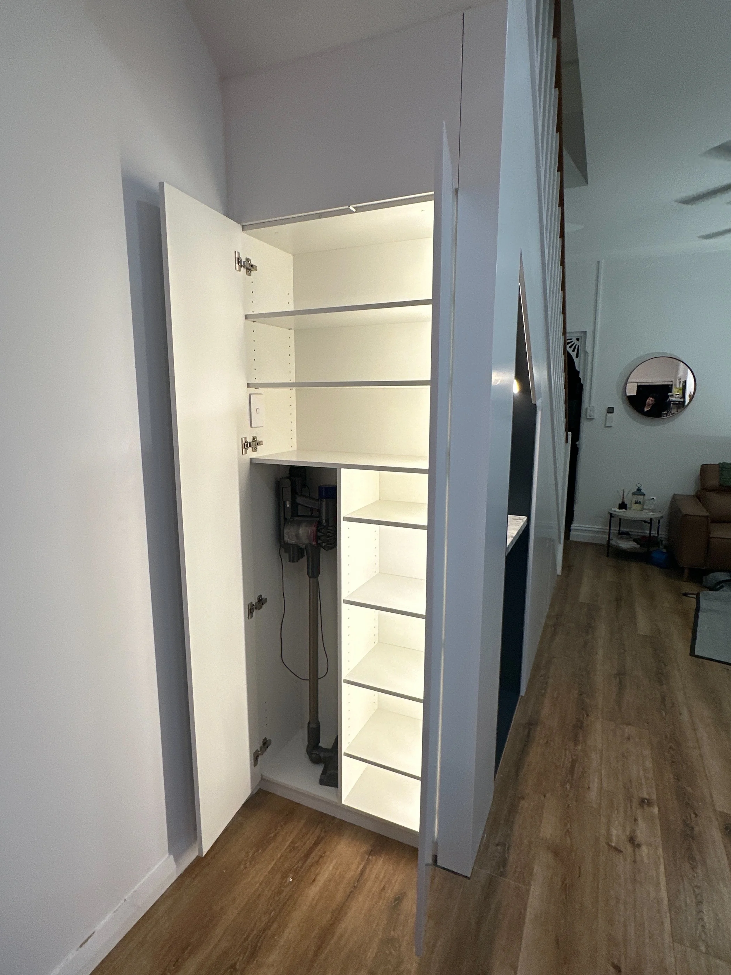 White polyurethane cabinetry under stairs with LED strip lighting inside