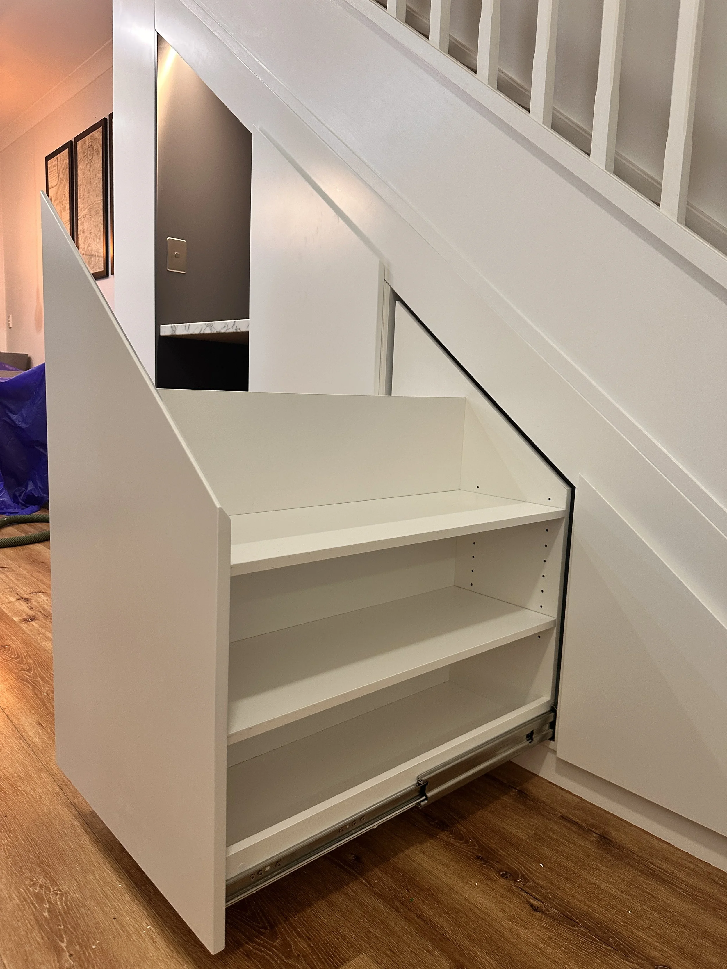 White polyurethane under stairs cabinetry with hidden storage solutions