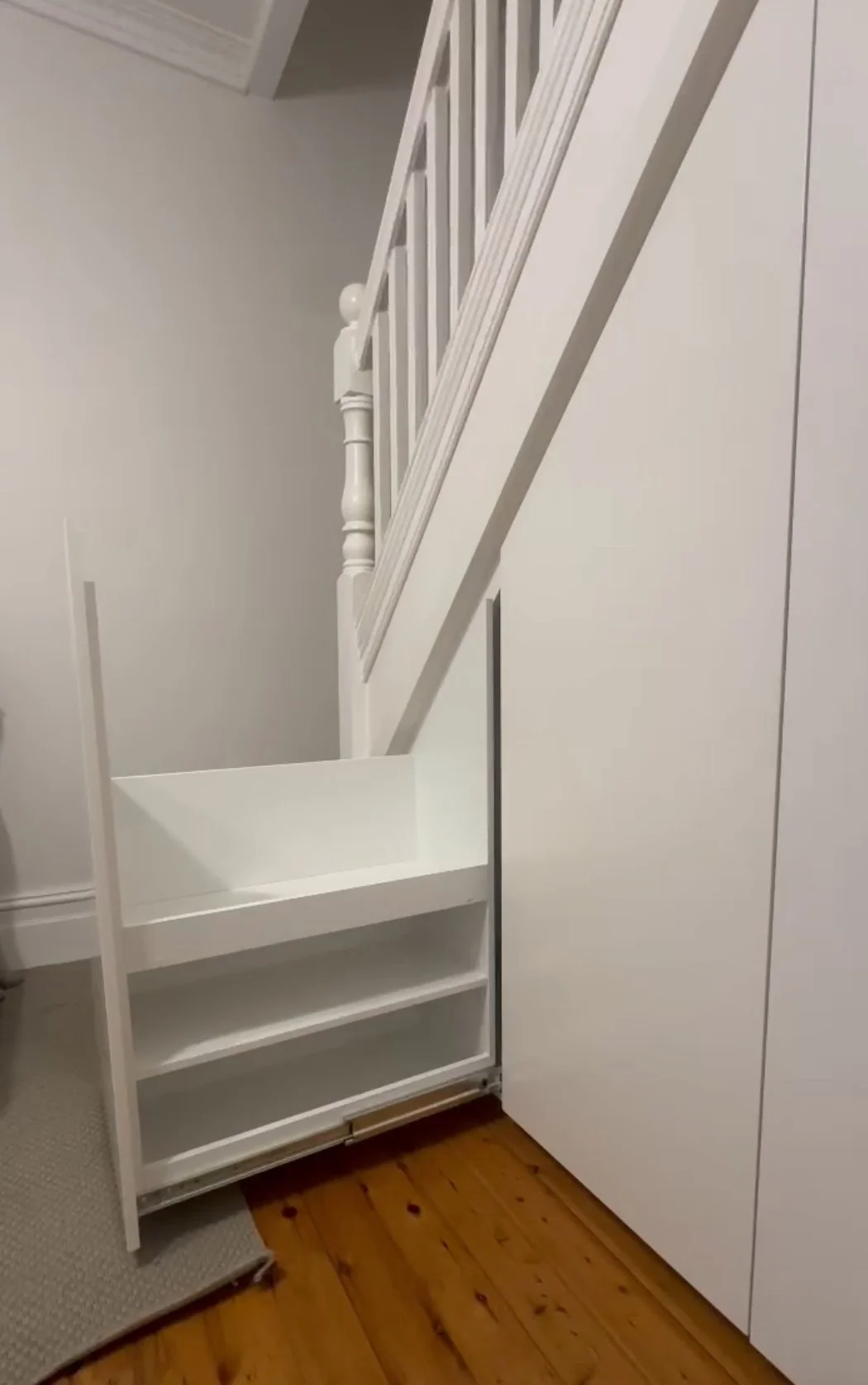 Custom under stairs cabinetry in white polyurethane with heavy duty pull-out drawers