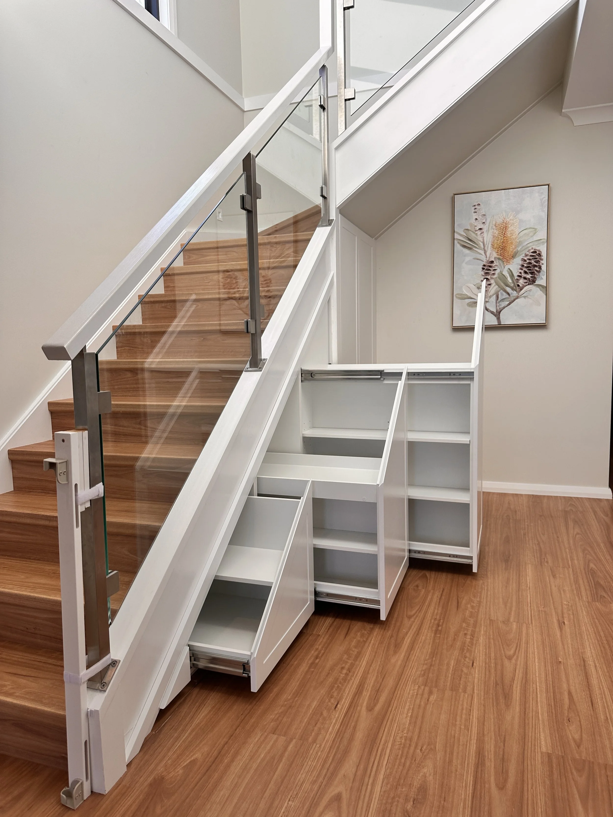 Custom under stairs cabinetry in white polyurethane with heavy duty pull-out drawers