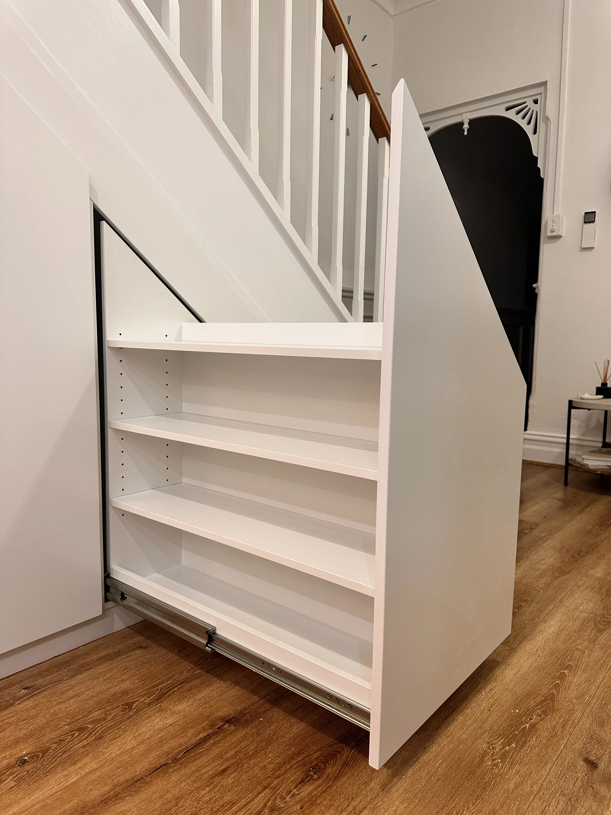Custom fitted cabinetry beneath staircase with storage drawers