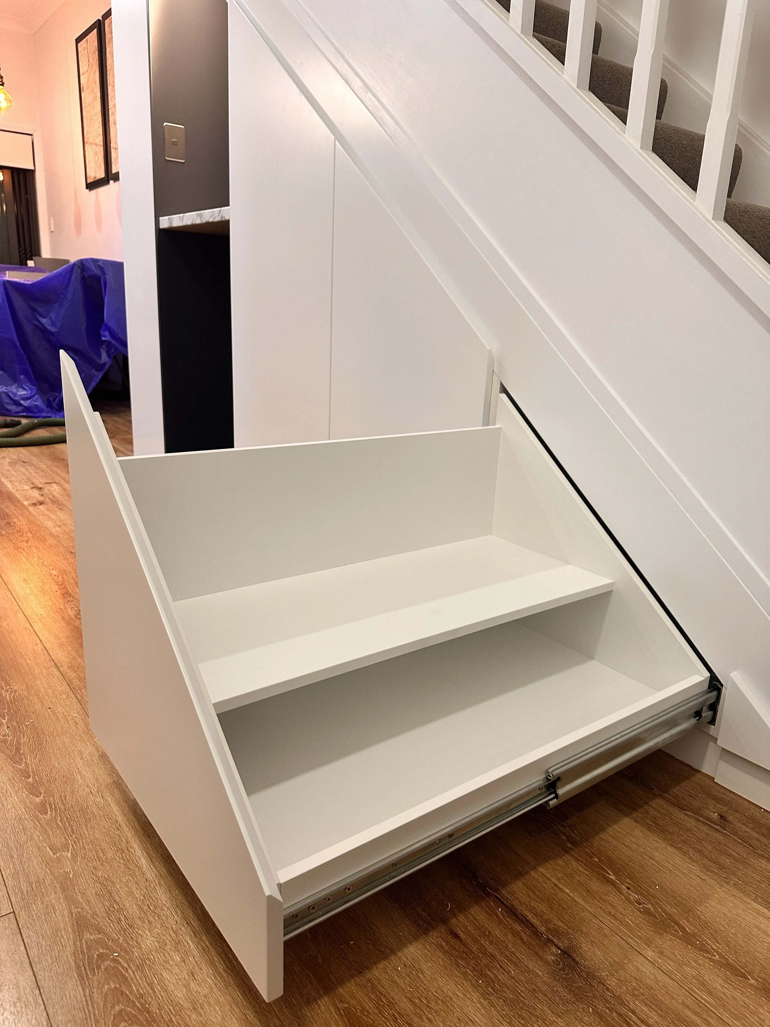 Custom under stairs cabinetry with integrated shoe storage compartments