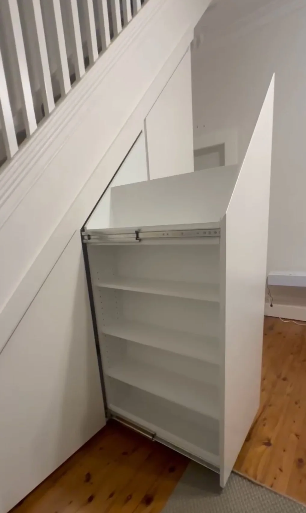 Custom under stairs cabinetry in white polyurethane with heavy duty pull-out drawers