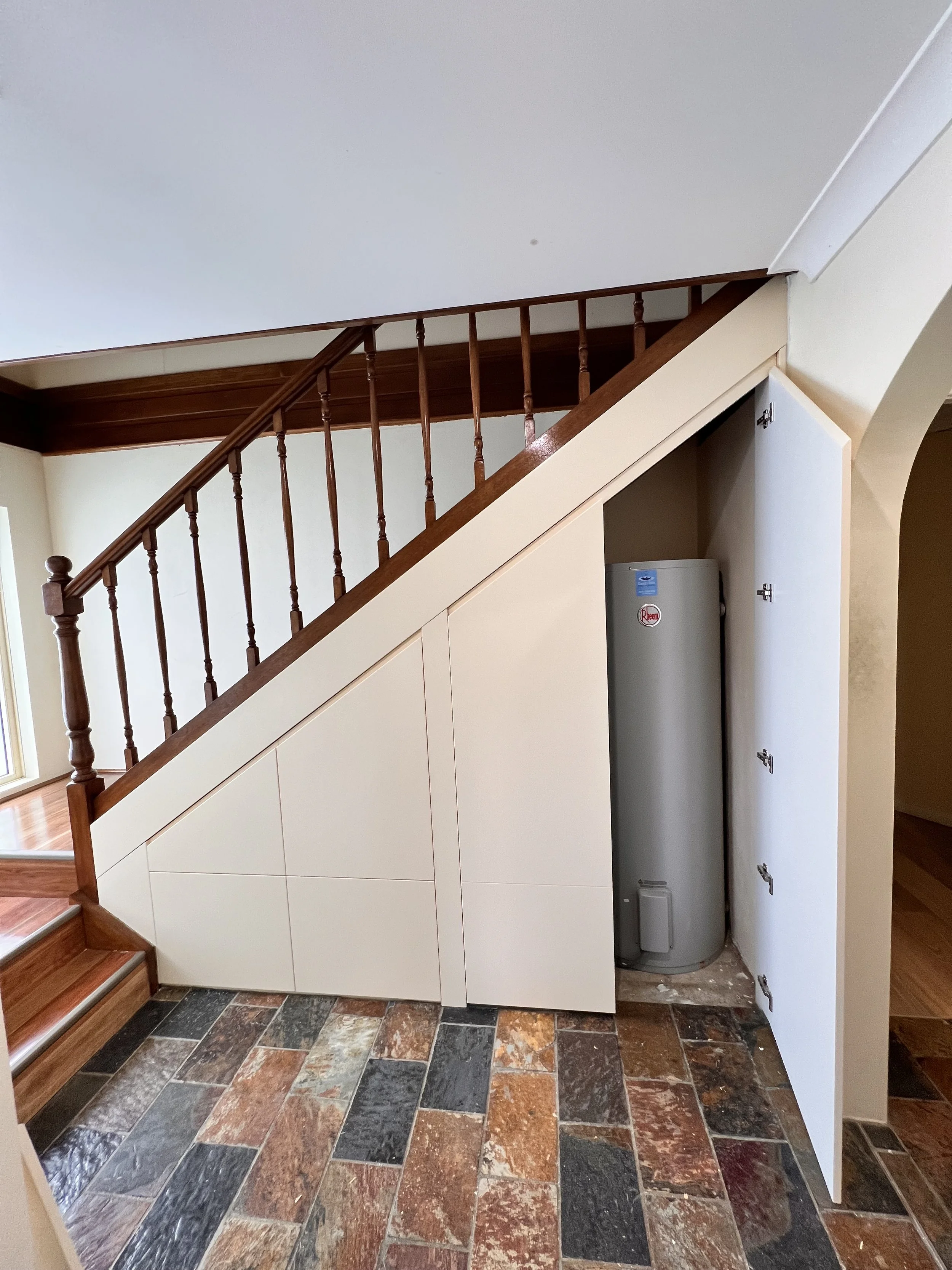 Sleek polyurethane cabinetry with hidden compartments under stairs