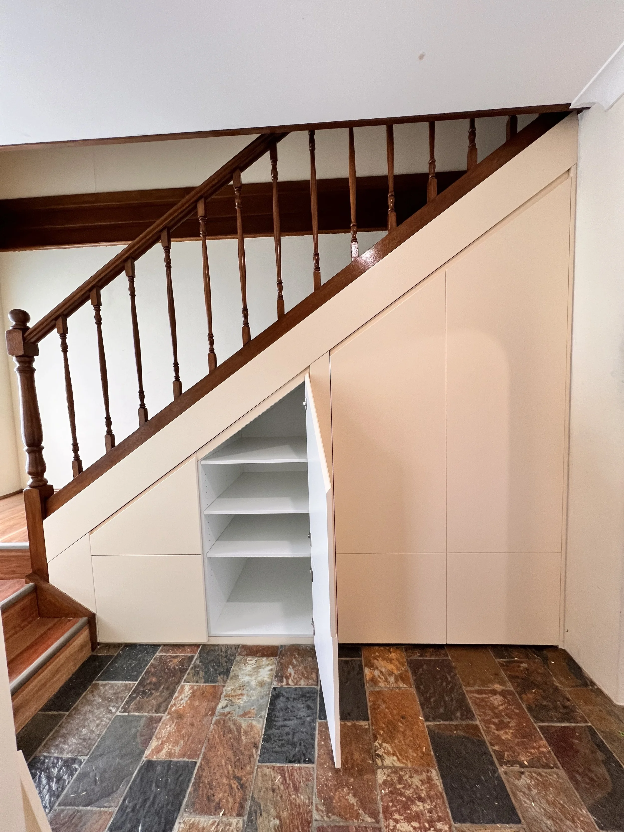 Beige polyurethane under stairs cabinetry with hidden storage solutions