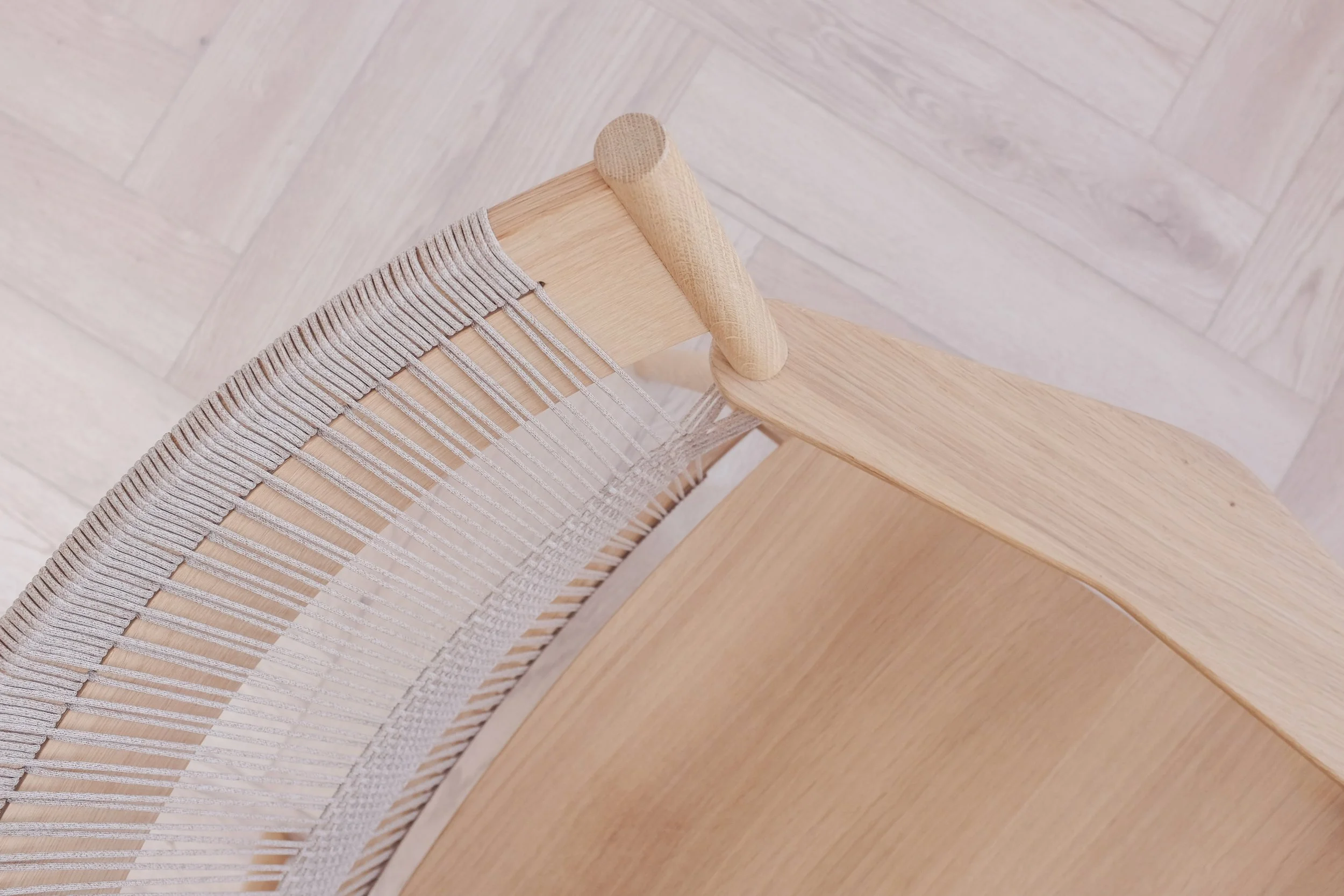 Woven detailing on the top of the backrest of oak easy chair.