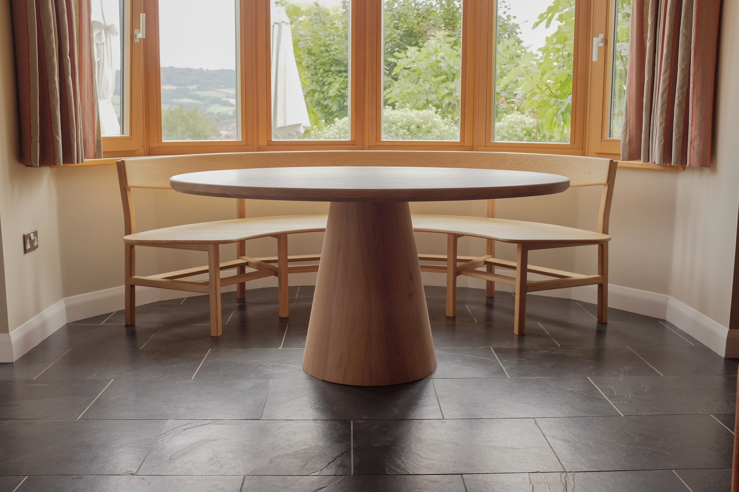 The Wye dining set, a curved oak bench seat and oval table made bespoke from solid oak to fit in bay window.