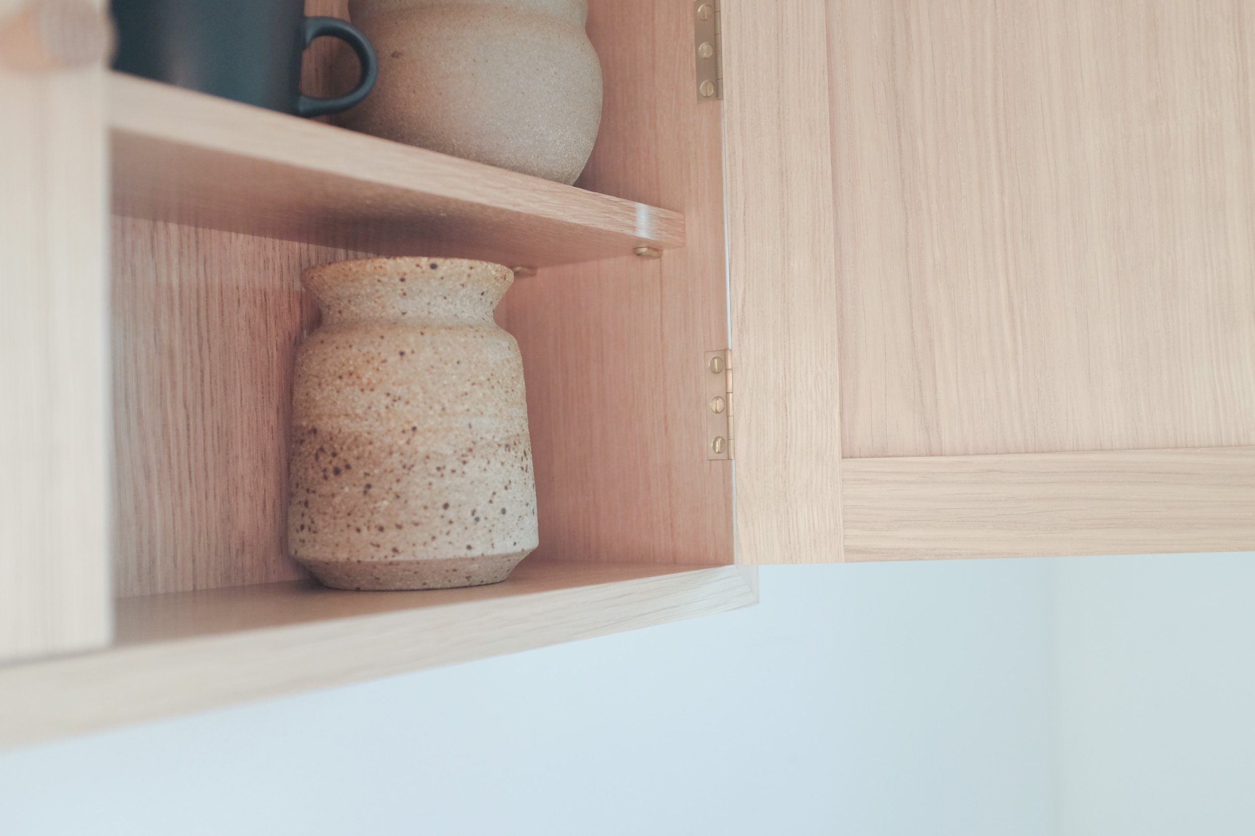 Rustic speckled pot inside oak wall cabinet