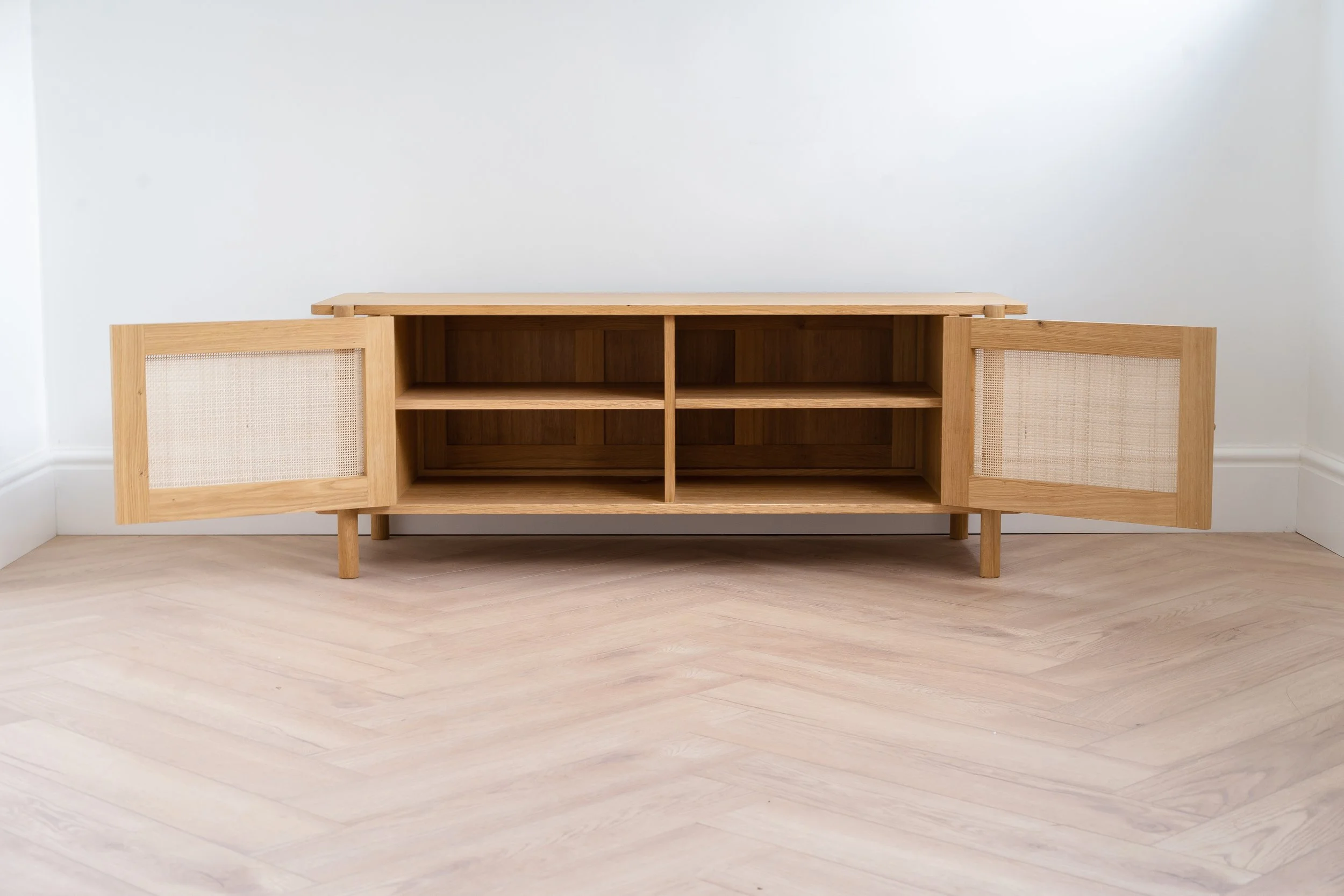 Large oak sideboard with both rattan doors open. Two shelves and a centre divider inside the cabinet.