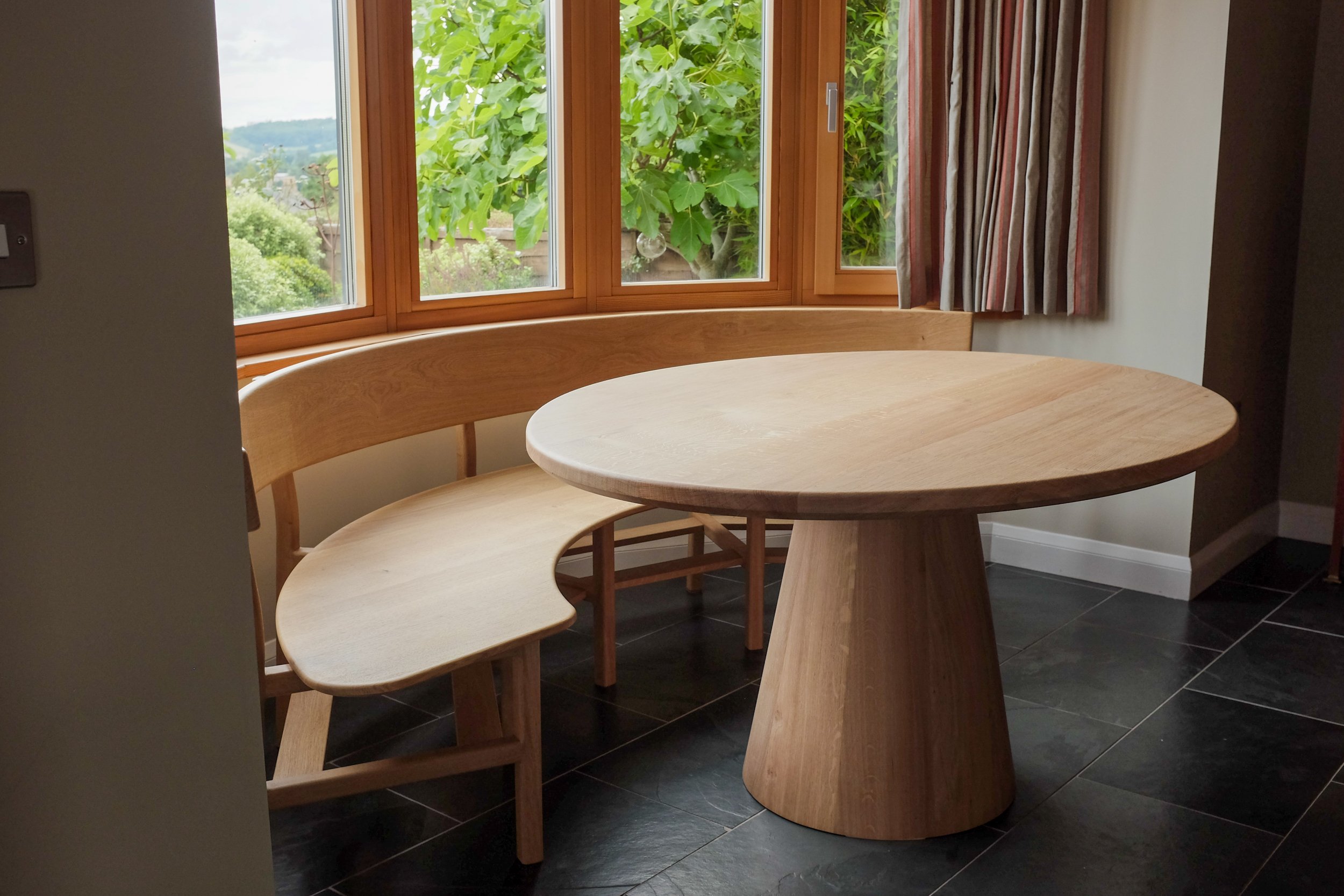 The Wye dining set, a curved oak bench seat and oval table made bespoke from solid oak to fit in bay window.