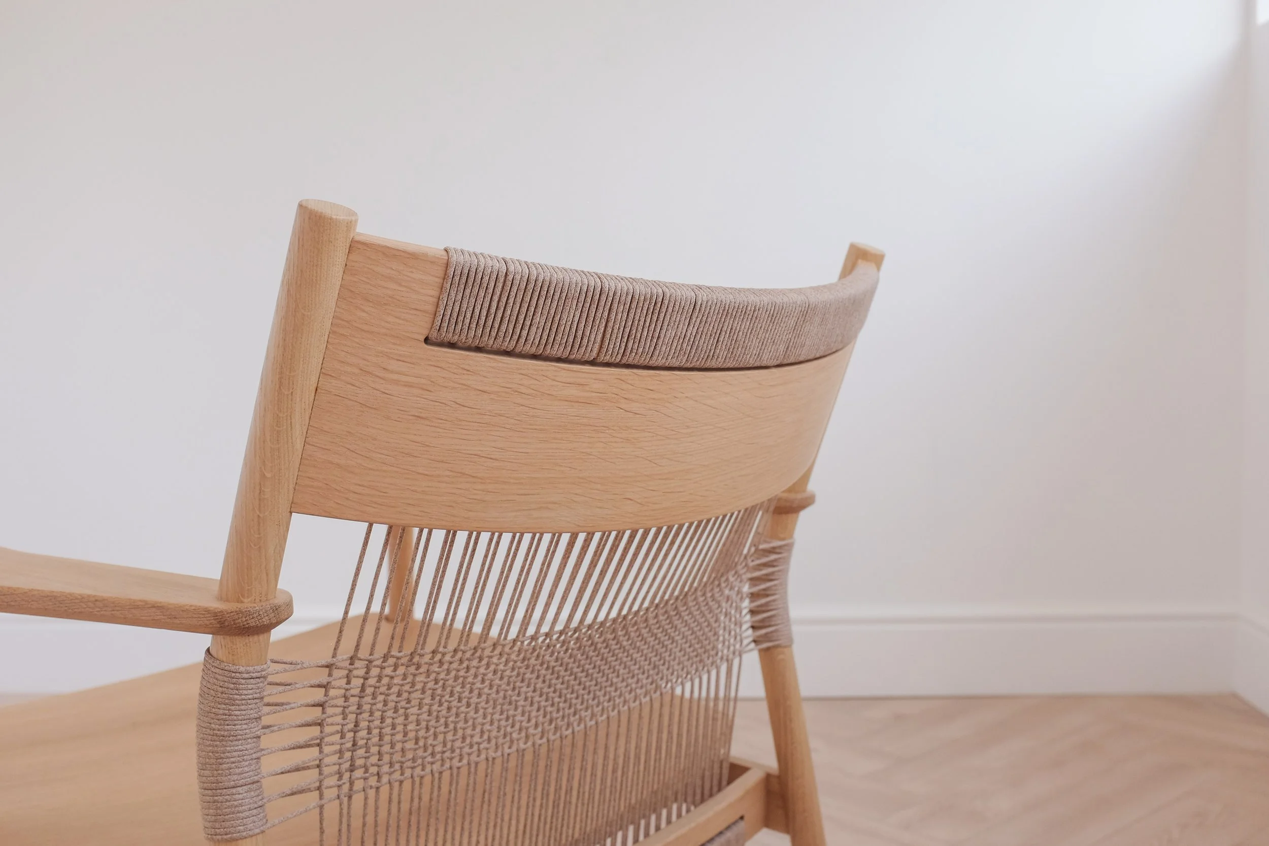 Woven cord detail at top of backrest on solid oak easy chair.