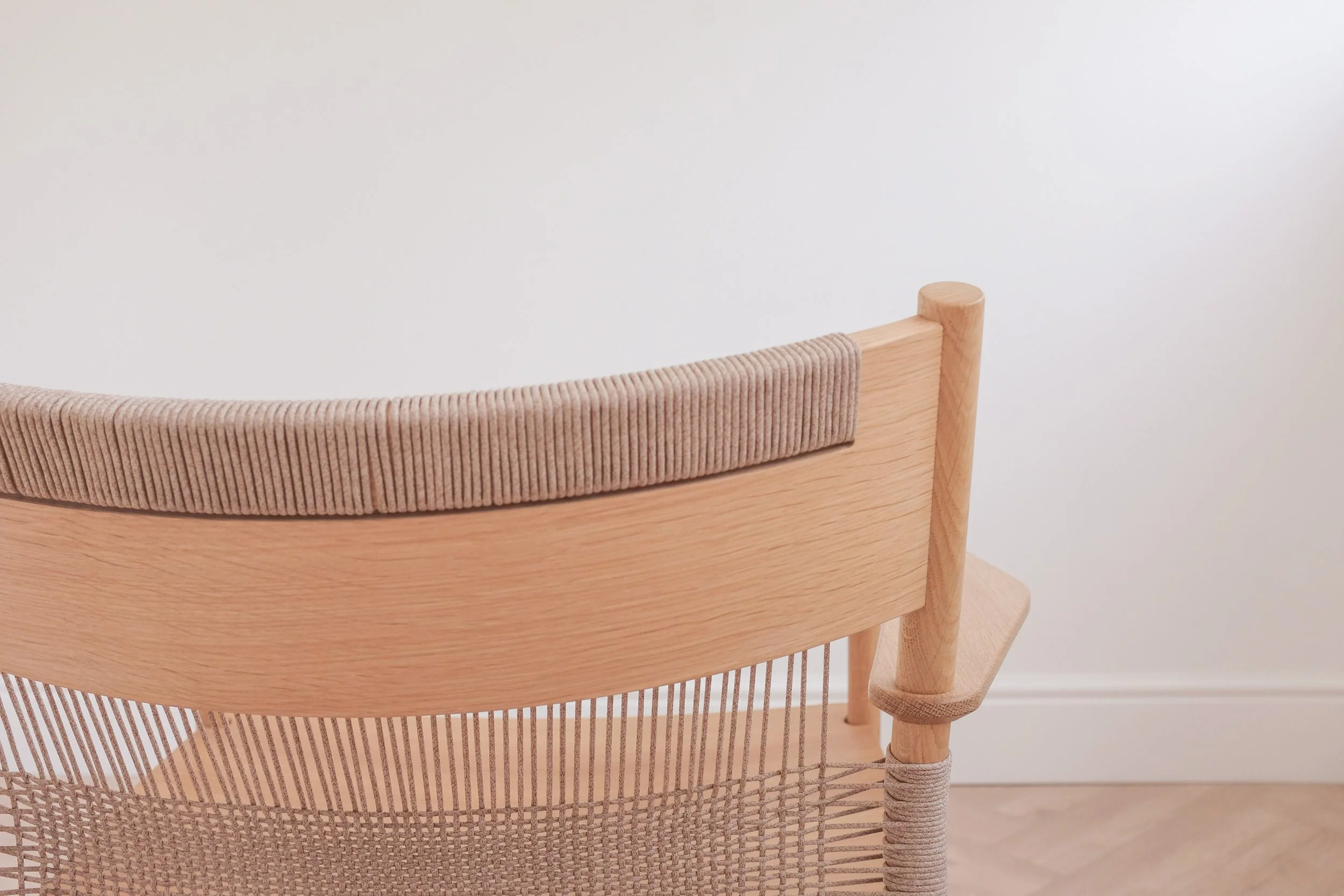 Woven cord detail at top of backrest on solid oak easy chair.