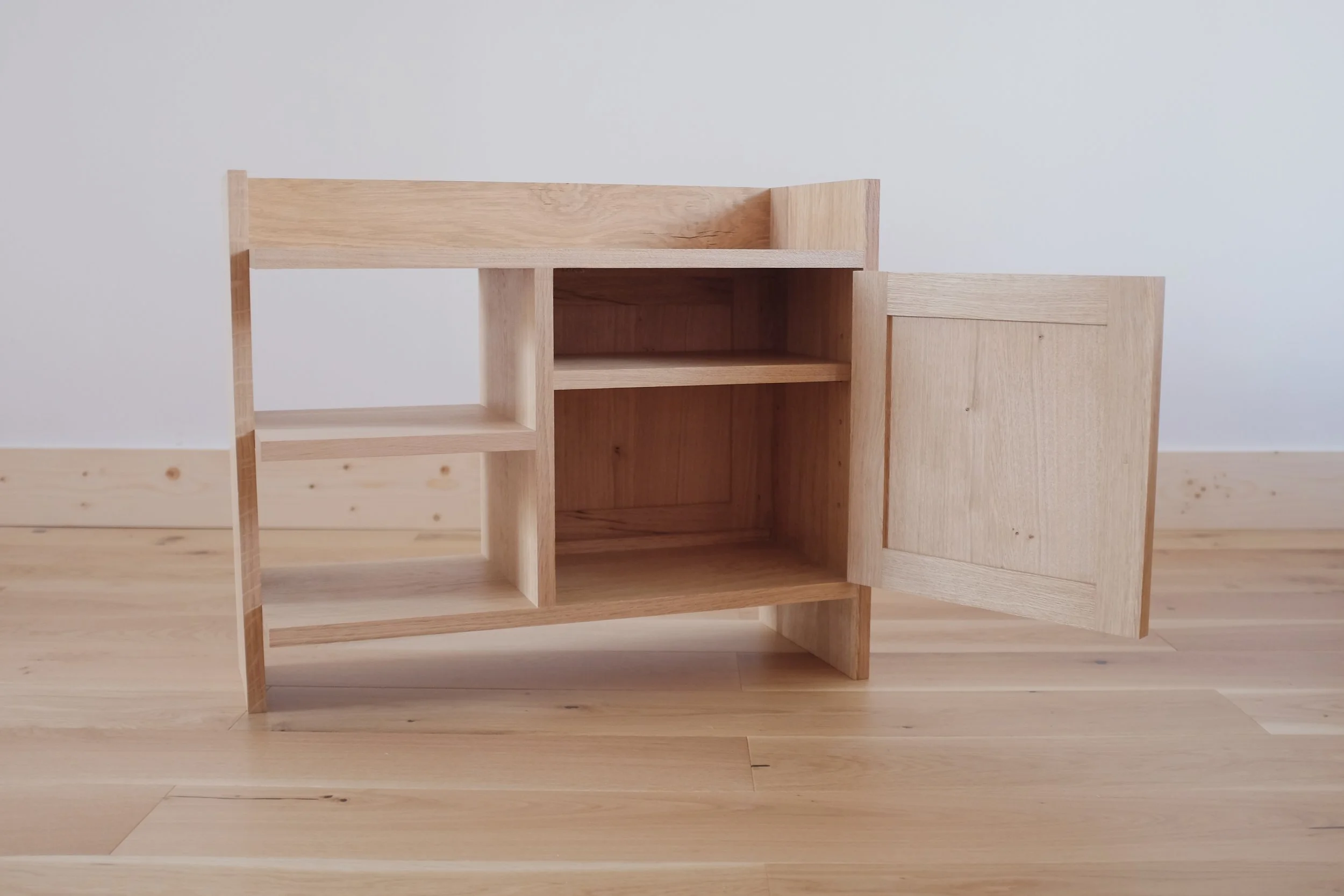 Shelves inside oak bedside cabinet with open door.