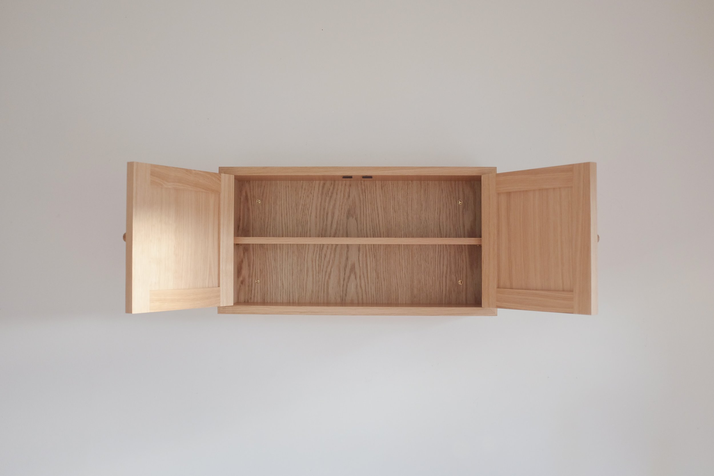 Wall cabinet with open doors to show shelf inside.