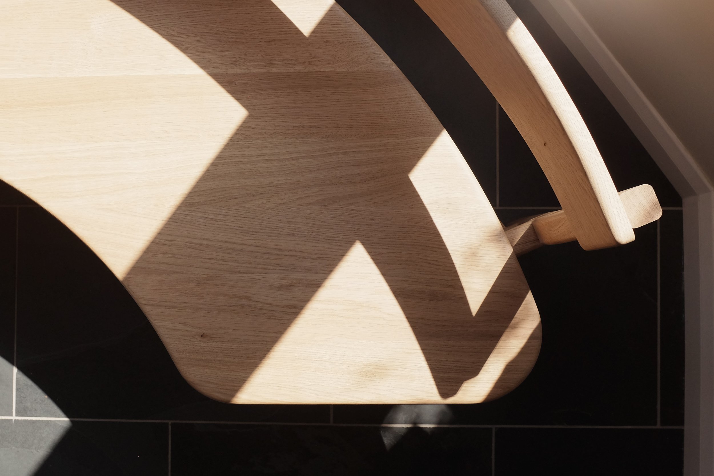 Curved solid oak seat in shadows on the Wye bench.