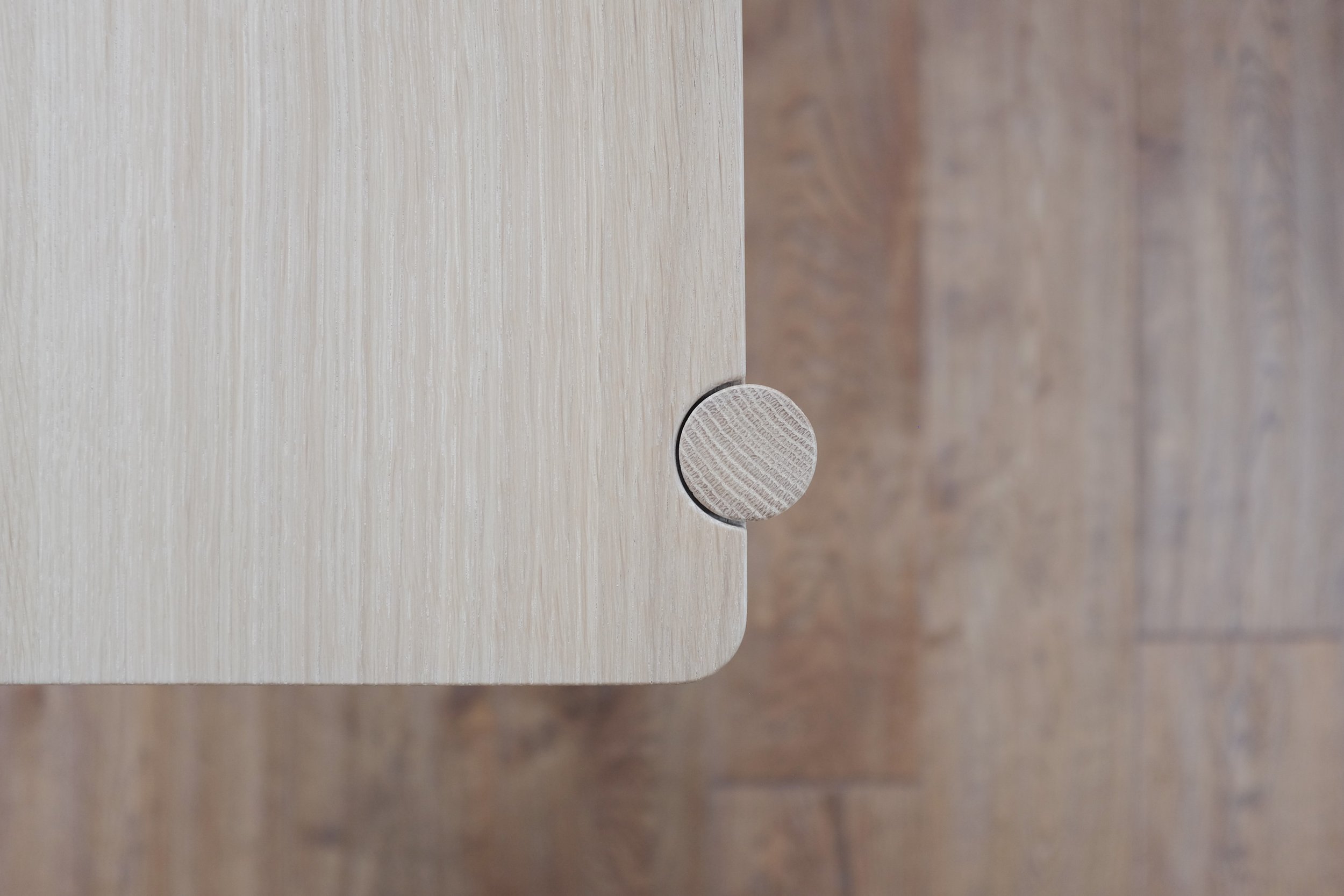 Circular cutaway detail where leg and top panel of the drawers meet.