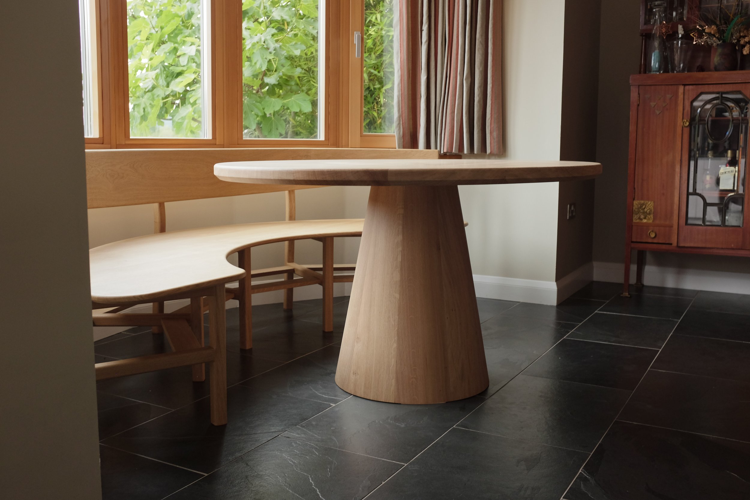 The Wye dining set, a curved oak bench seat and oval table made bespoke from solid oak to fit in bay window.