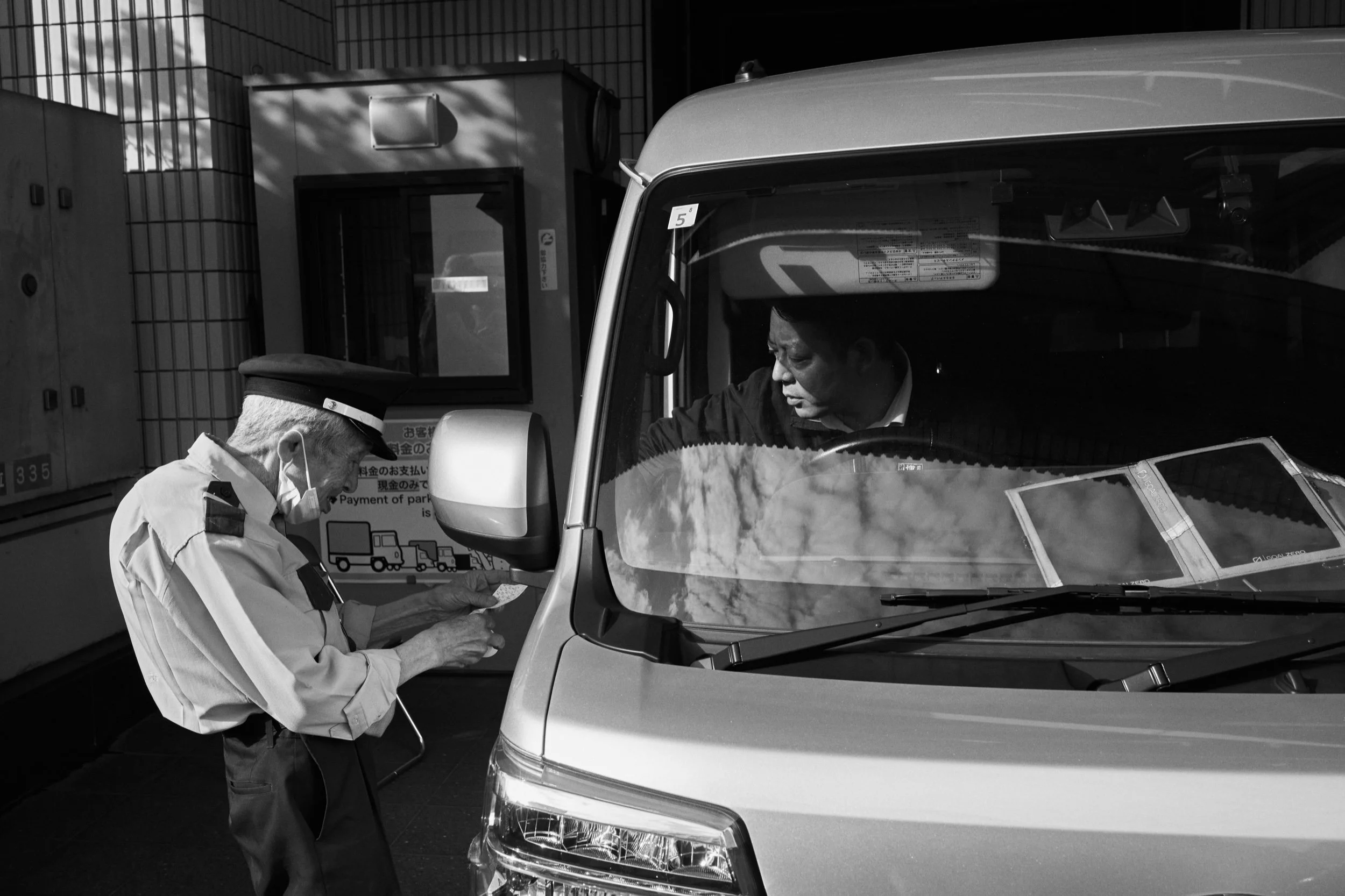 An attendant and driver at a car park entrance. Shinjuku, Tokyo.