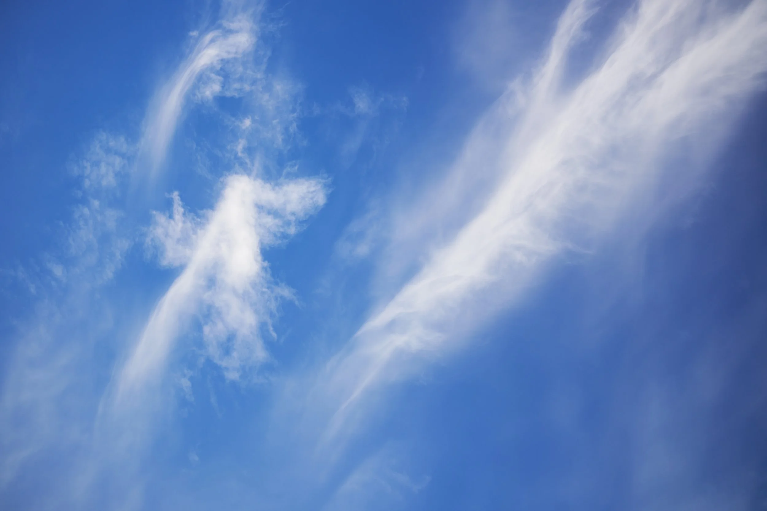 Sweeping white cloud forms against a deep blue sky.